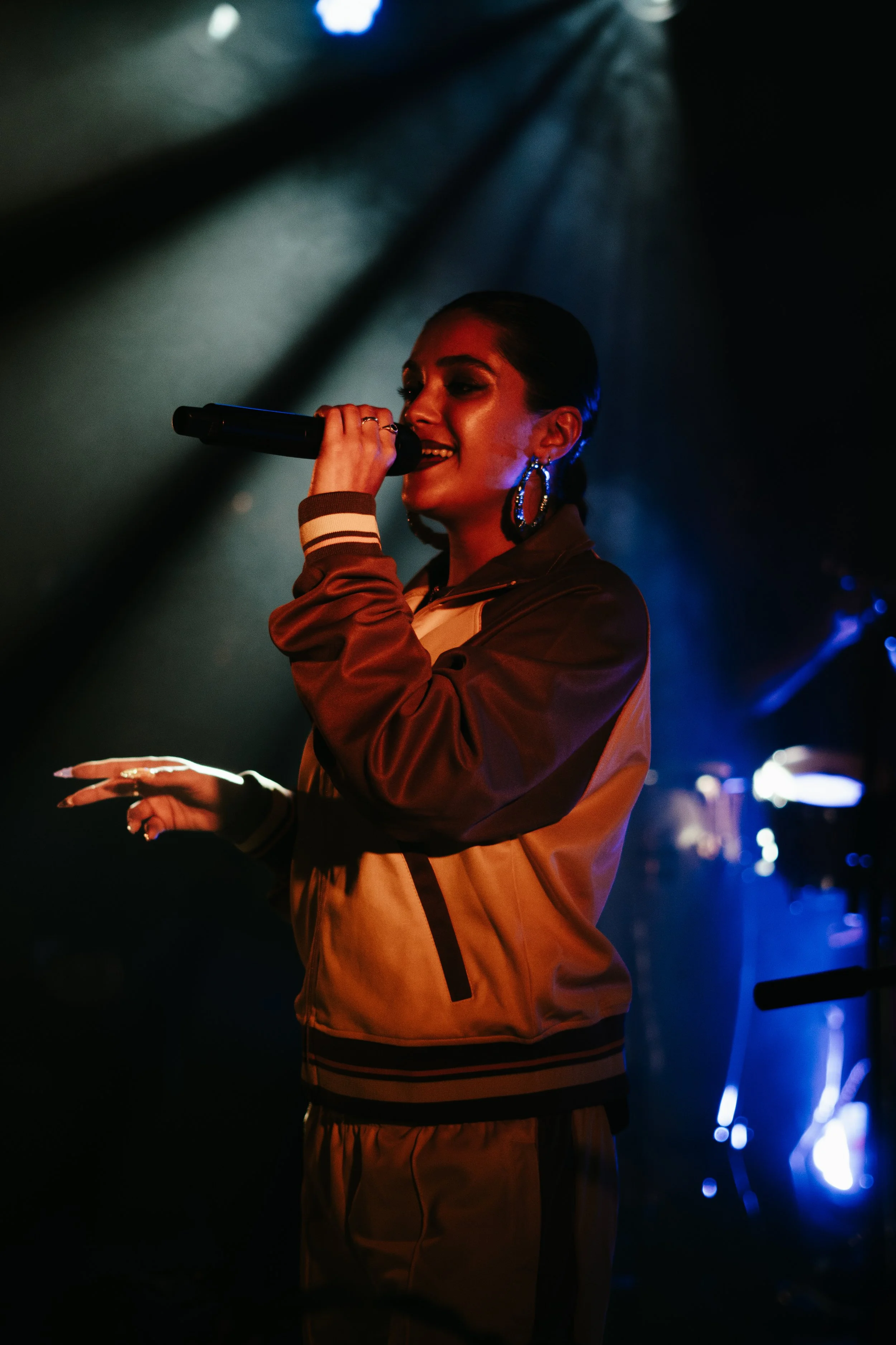 Jeune femme chantant avec un micro sur scène, éclairage tamisé, ambiance de concert.
