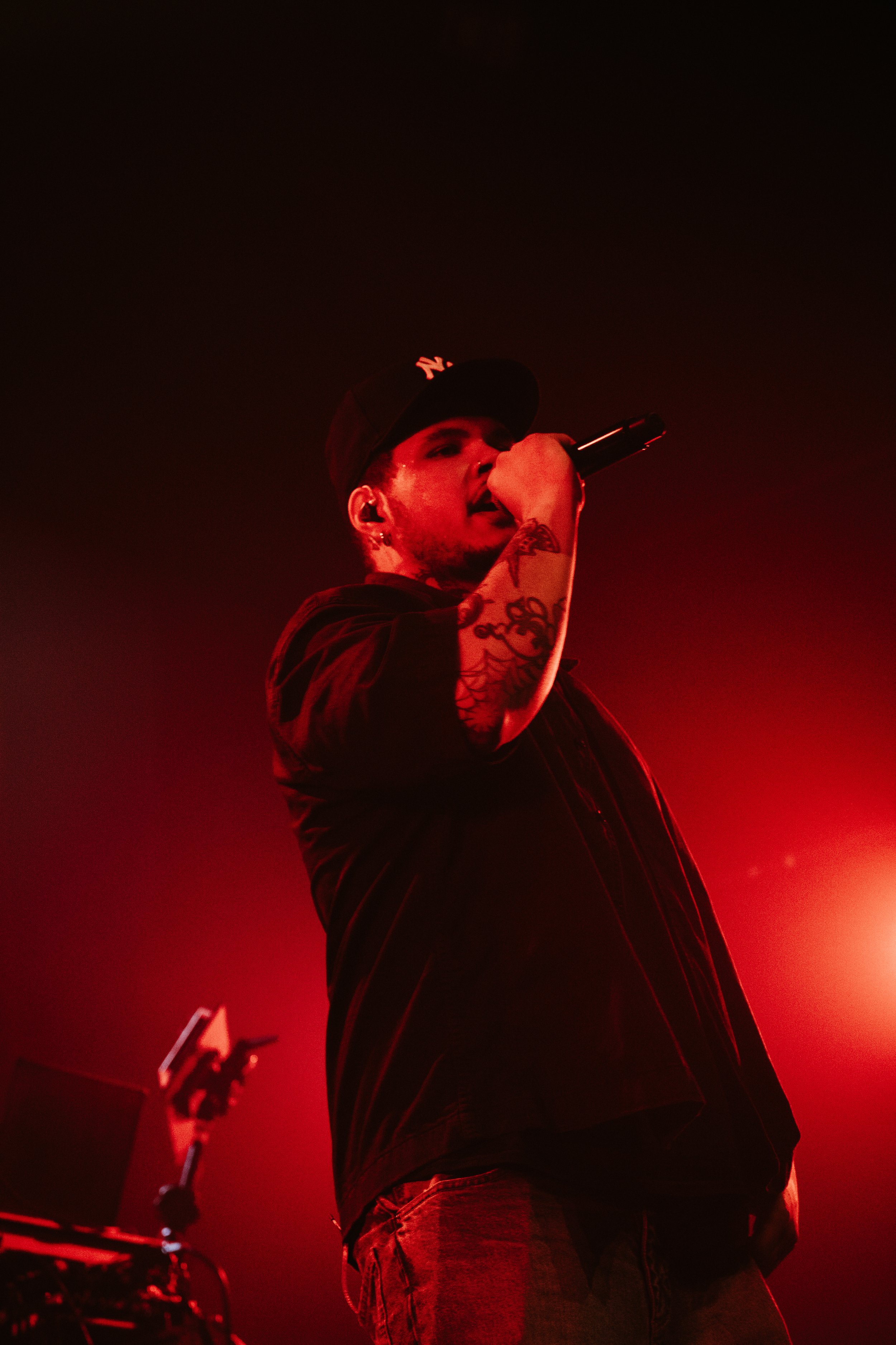 Homme rasant un micro sur scène avec un éclairage rouge.