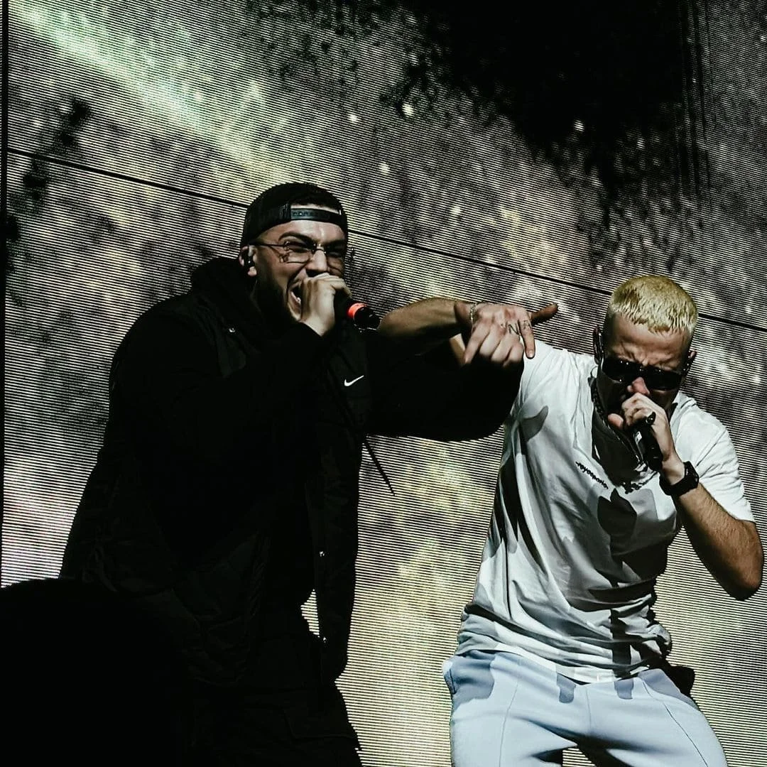 PLK ET TIF chantent et font un show sur scène, utilisant des microphones, avec un fond lumineux.