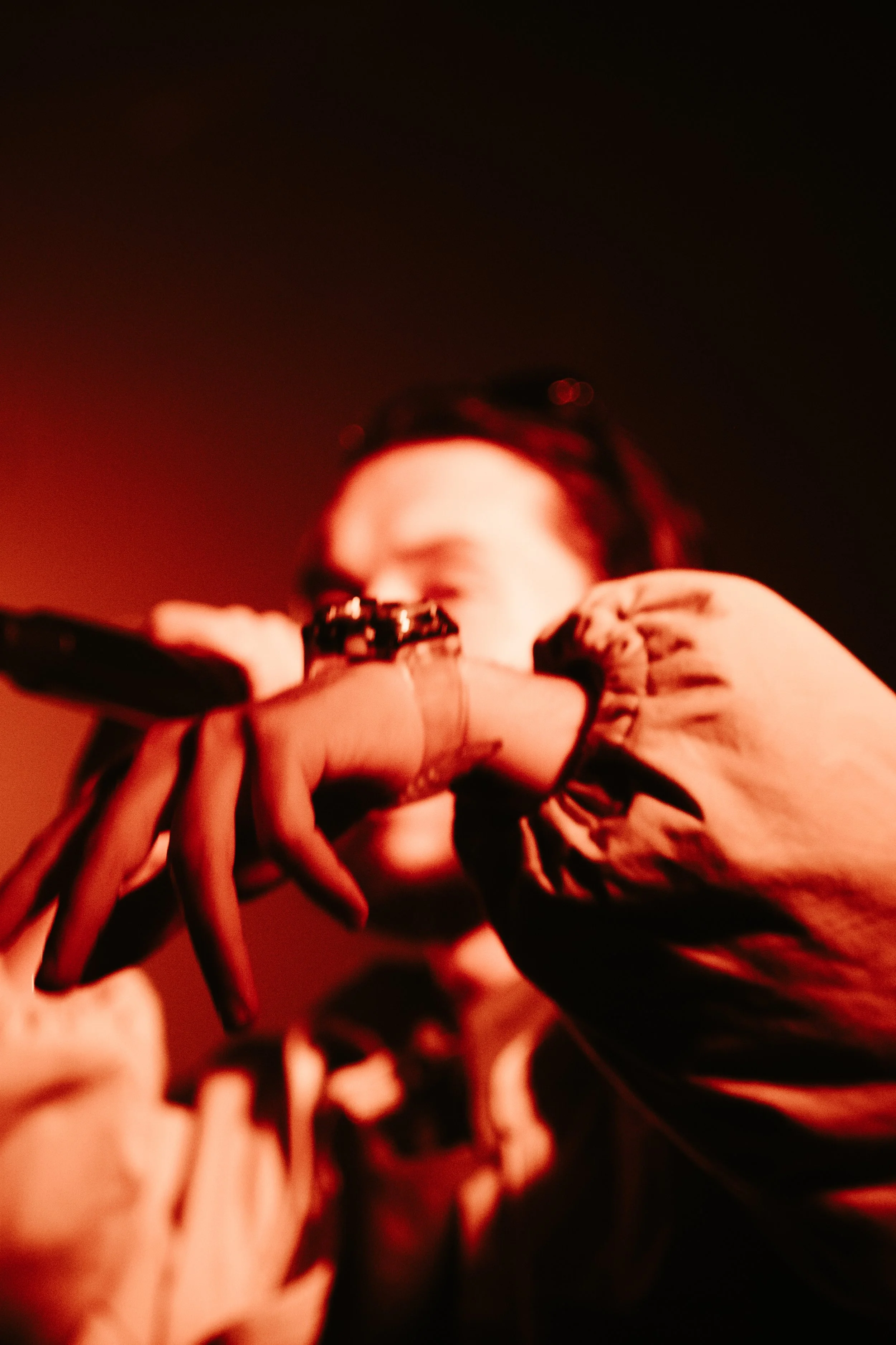 Une personne avec des lunettes de soleil, tenant un téléphone près du visage dans une lumière rouge