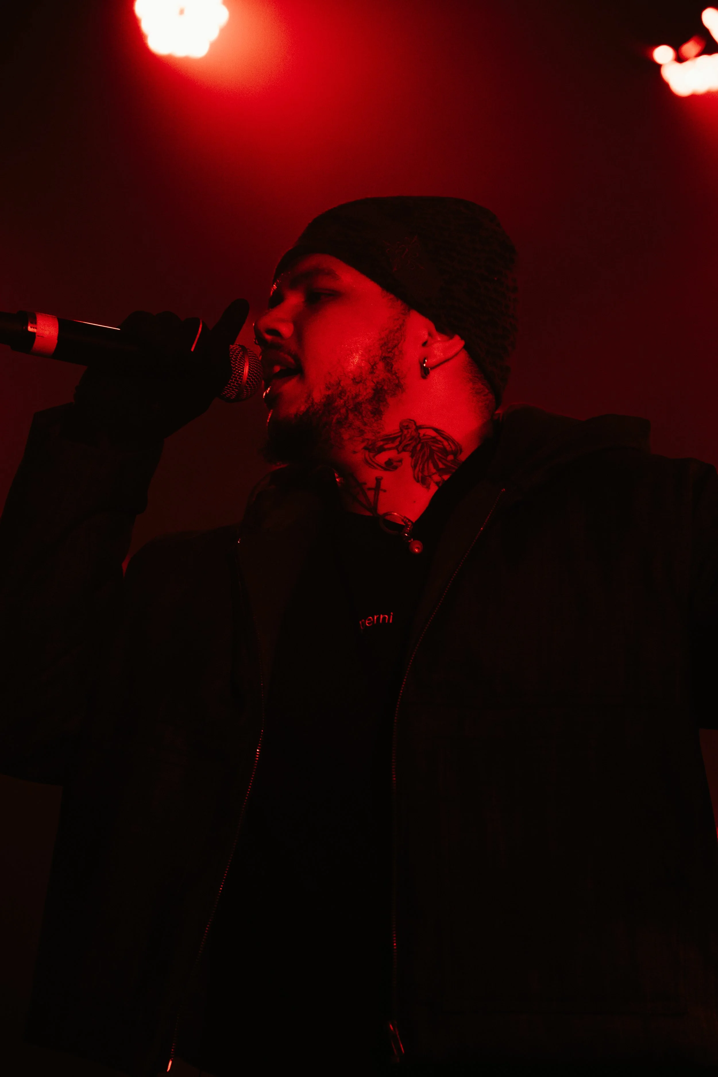 Un homme chante dans un microphone avec un éclairage rouge.