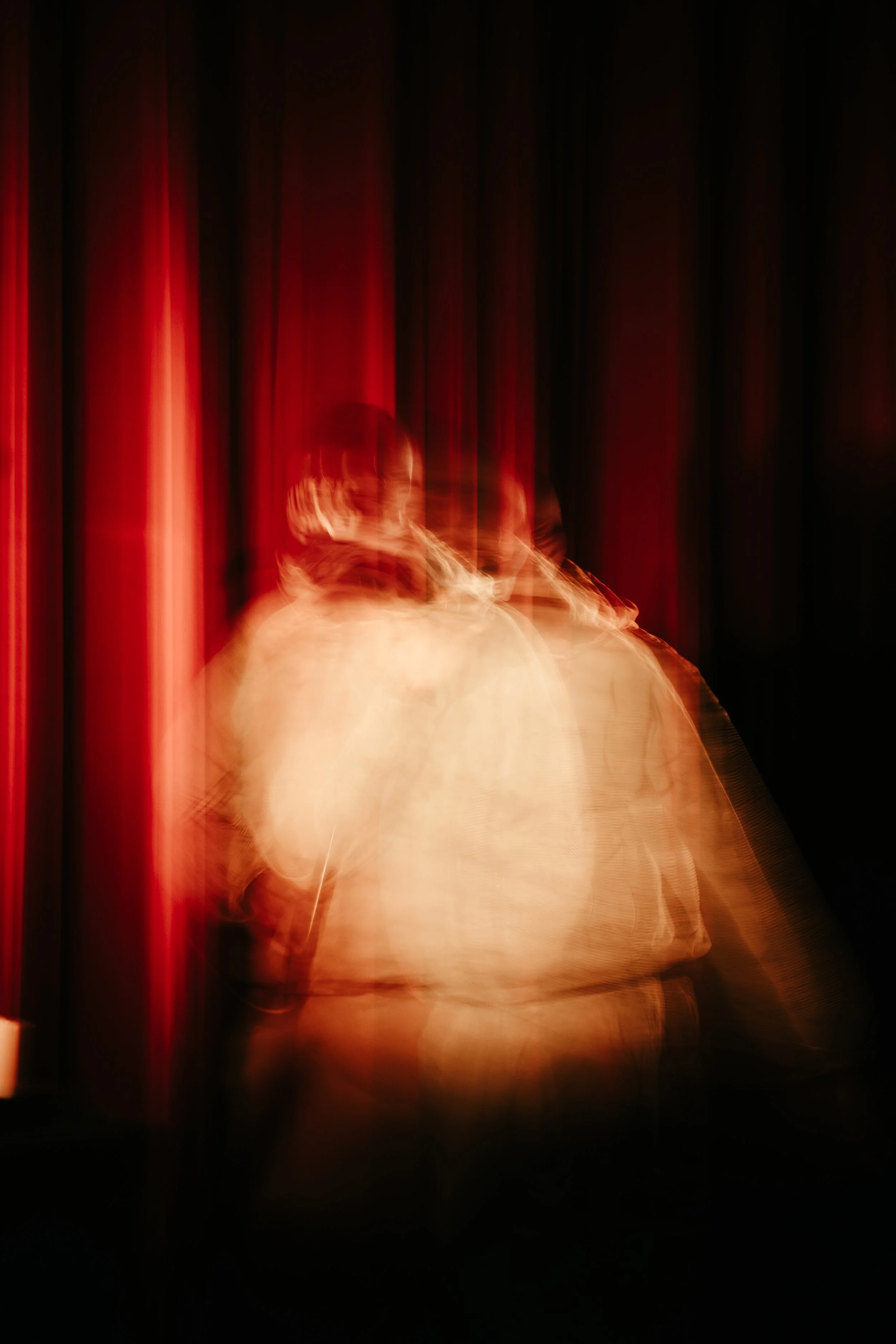 Une personne en train de monter sur scène, phénomène de mouvement flou avec des rideaux rouges en arrière-plan.