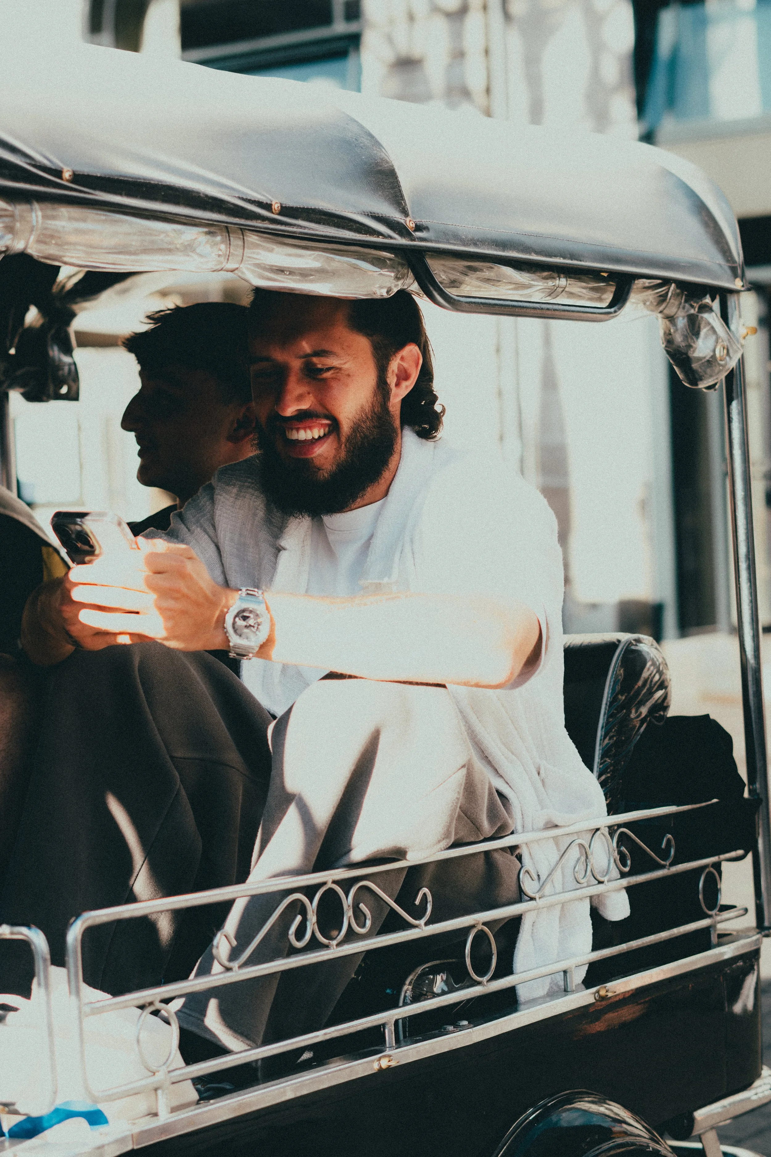 Un homme souriant utilisant son téléphone dans une rickshaw.