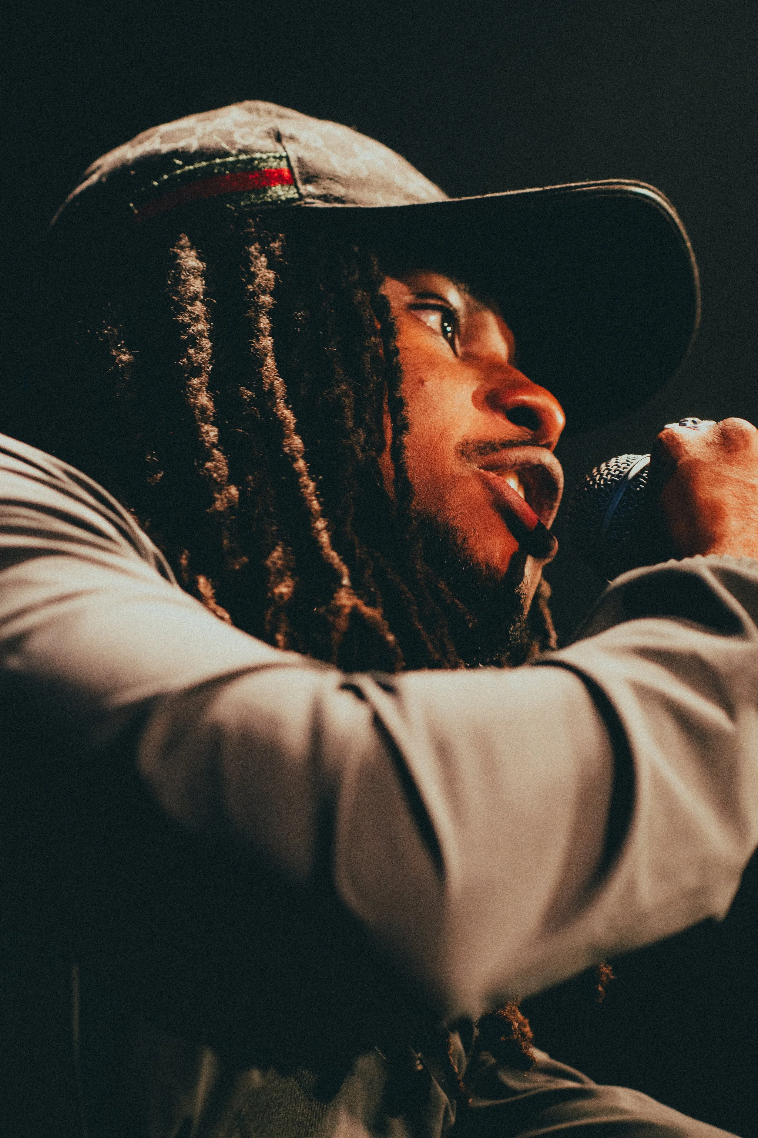 Un artiste chantant lors d'une performance, portant une casquette et tenant un microphone.