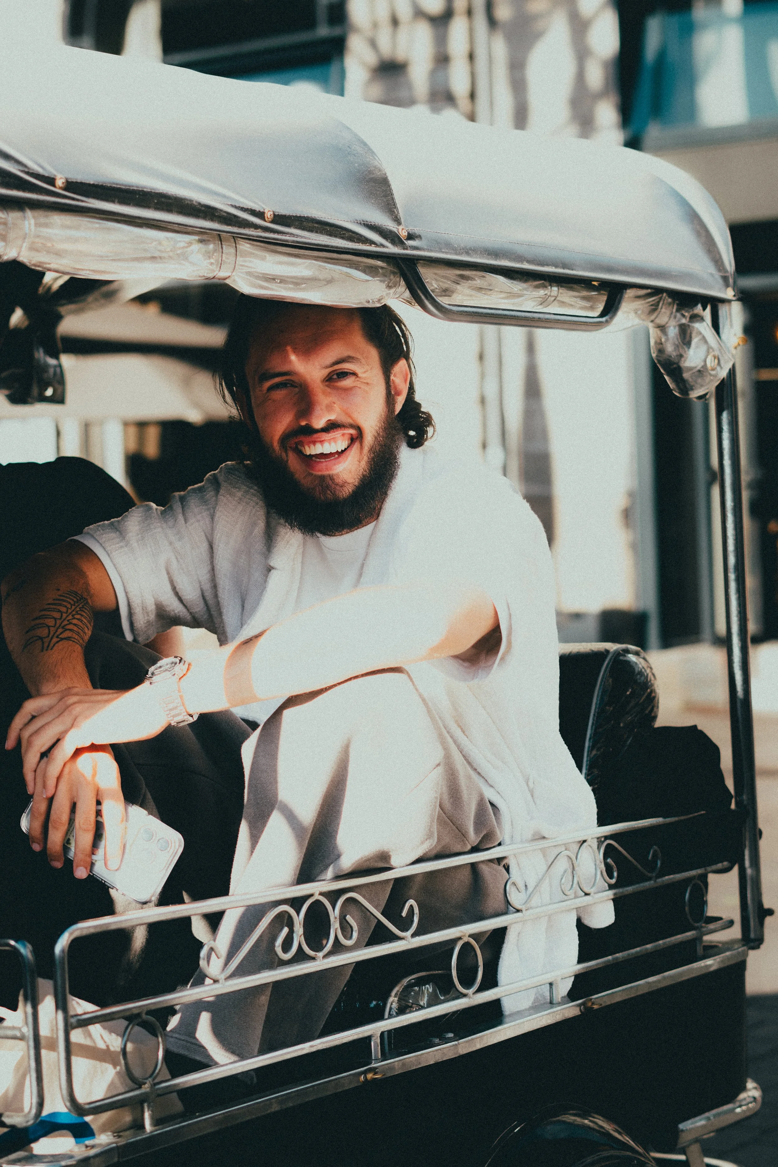 Homme souriant dans une tuk-tuk, tenant un téléphone portable