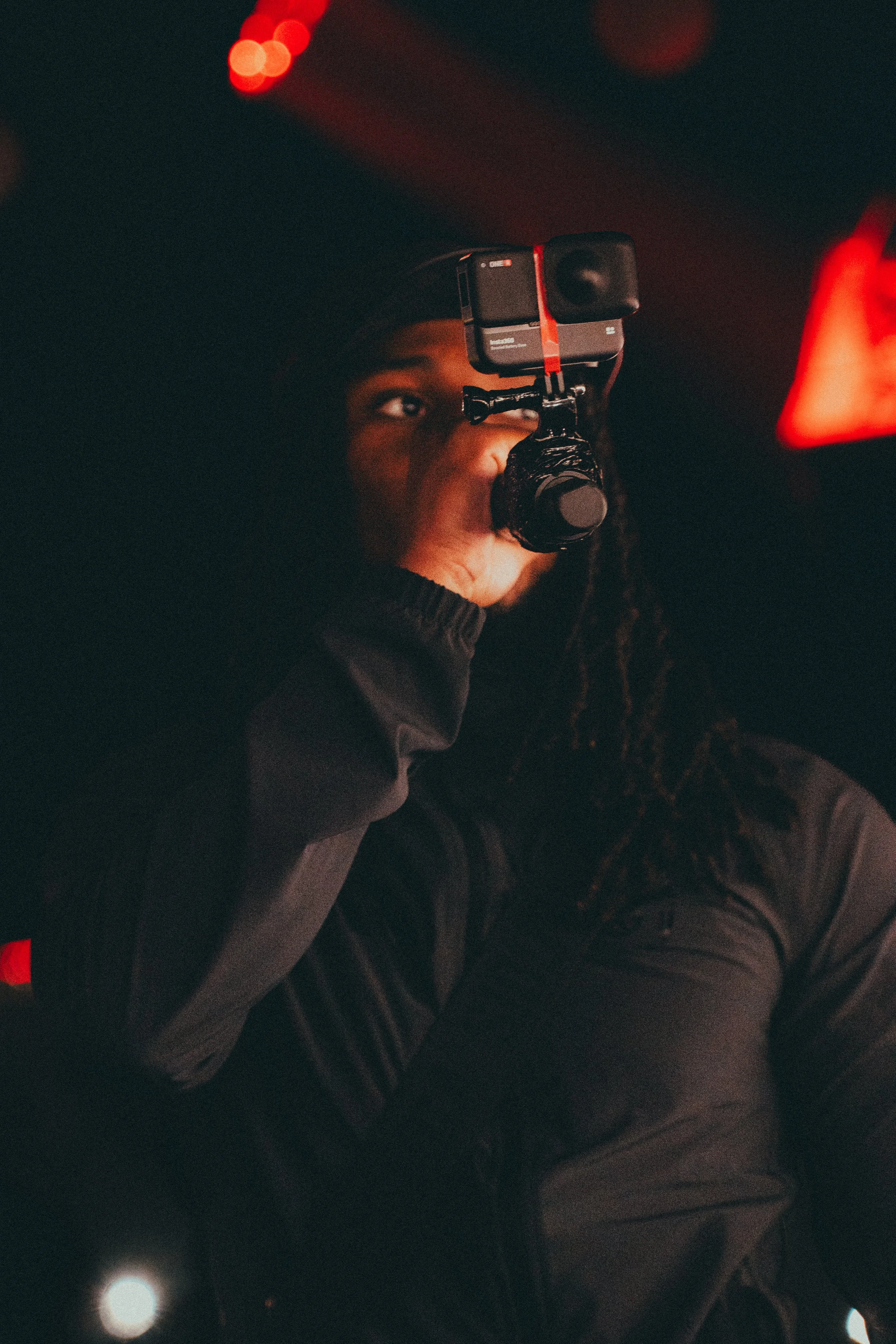 Une personne portant un casque et utilisant une caméra pour filmer dans un environnement sombre avec un éclairage rouge.