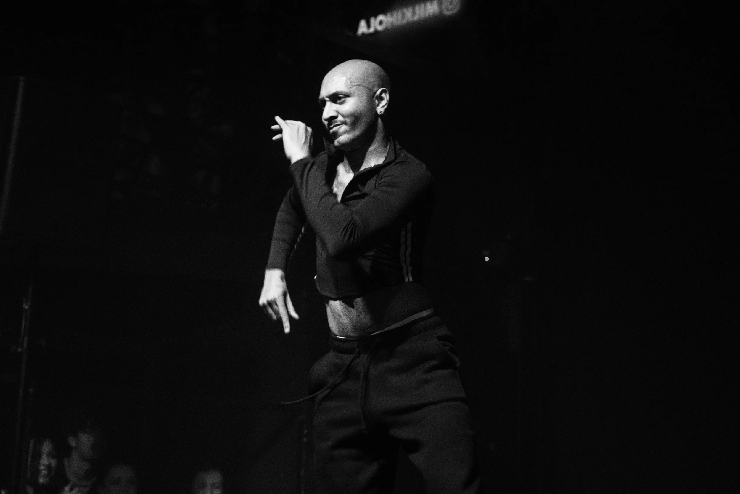 Une personne danser lors d'une performance sur scène, photographiée en noir et blanc.