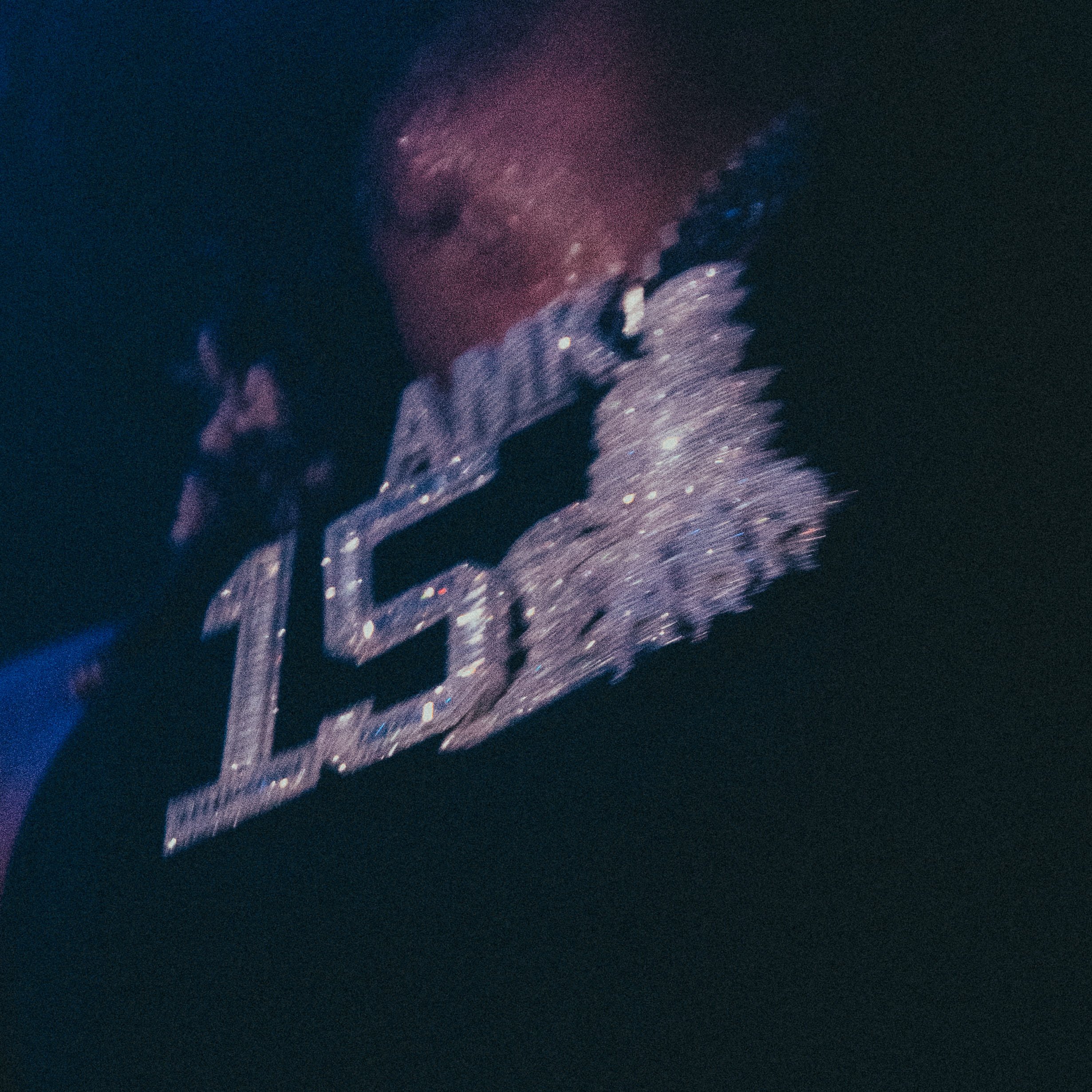 Une personne porte un collier ou une chaîne brillante et décorative, avec un fond sombre.