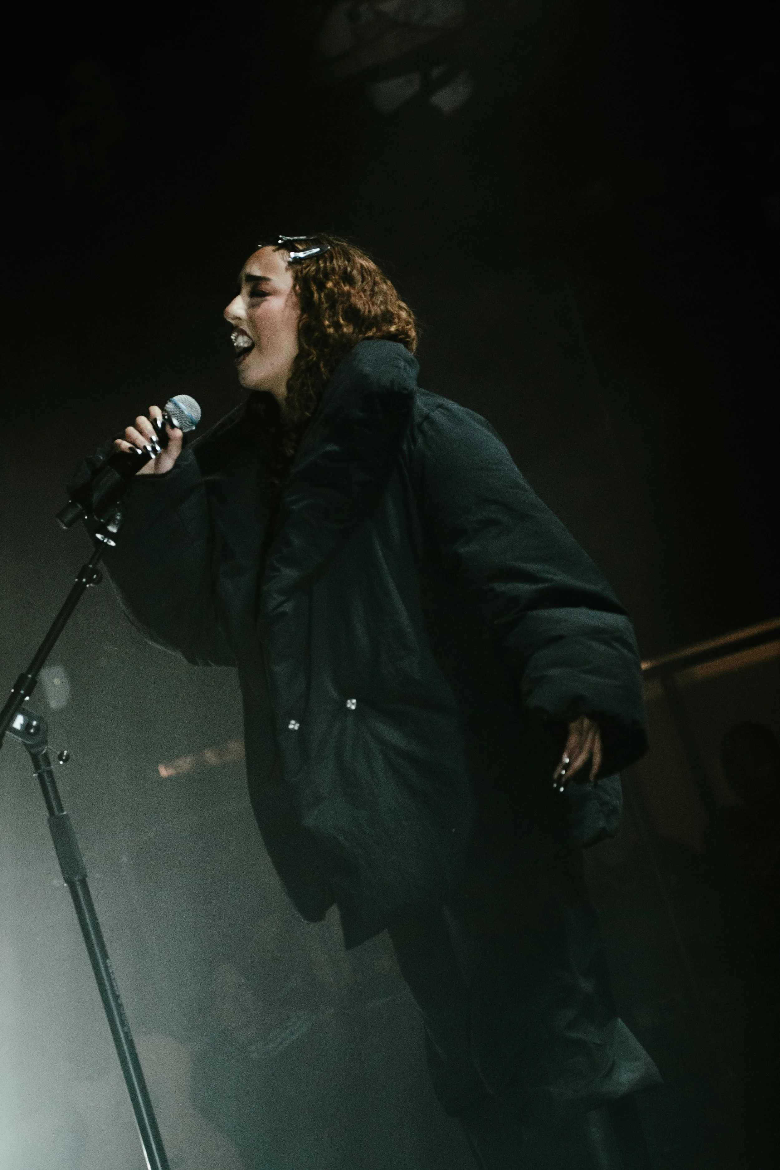 Une femme qui chante avec un micro dans une ambiance sombre.