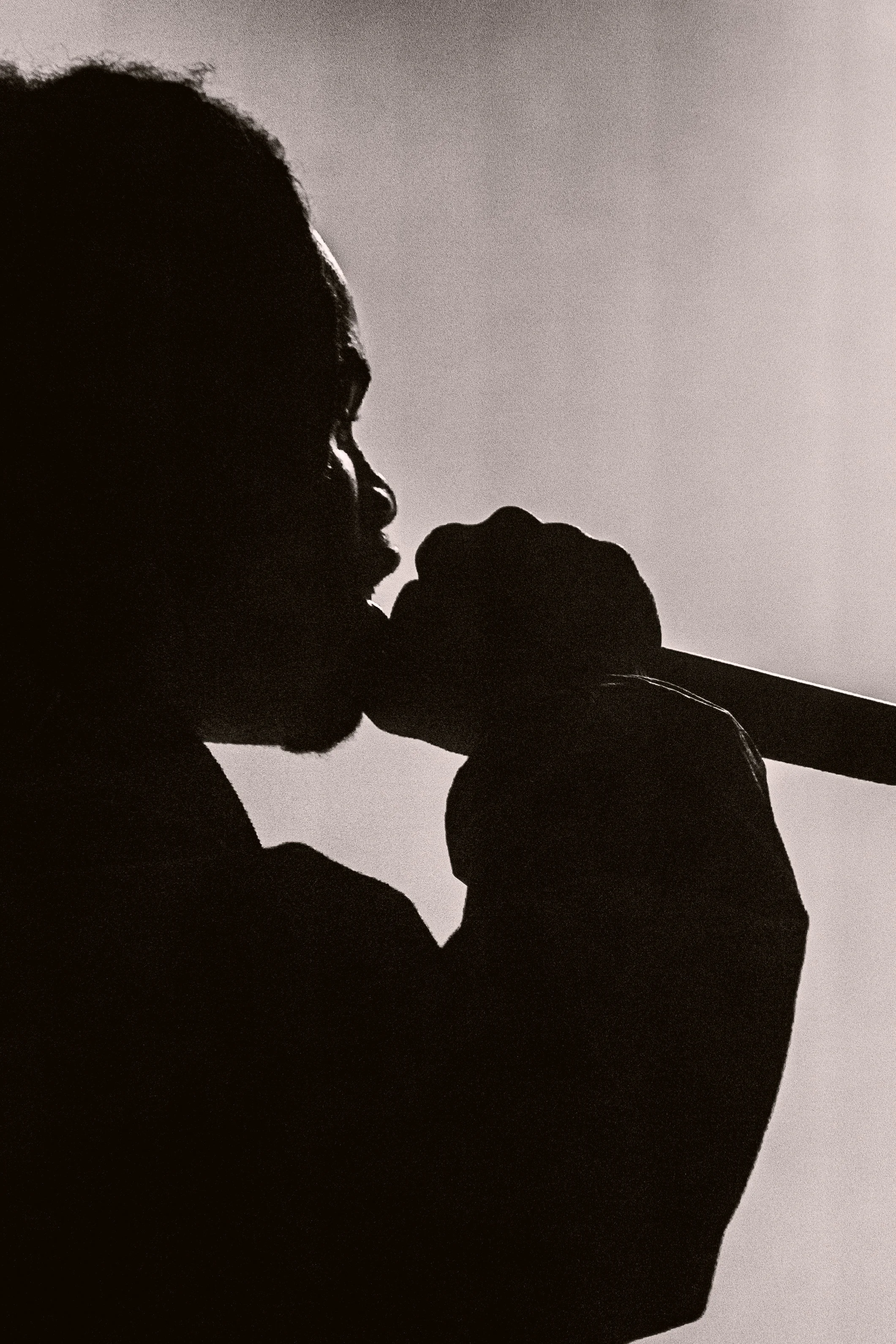 Silhouette d'un homme portant un casque de chantier et tenant un marteau, vu de profil, en contre-jour.