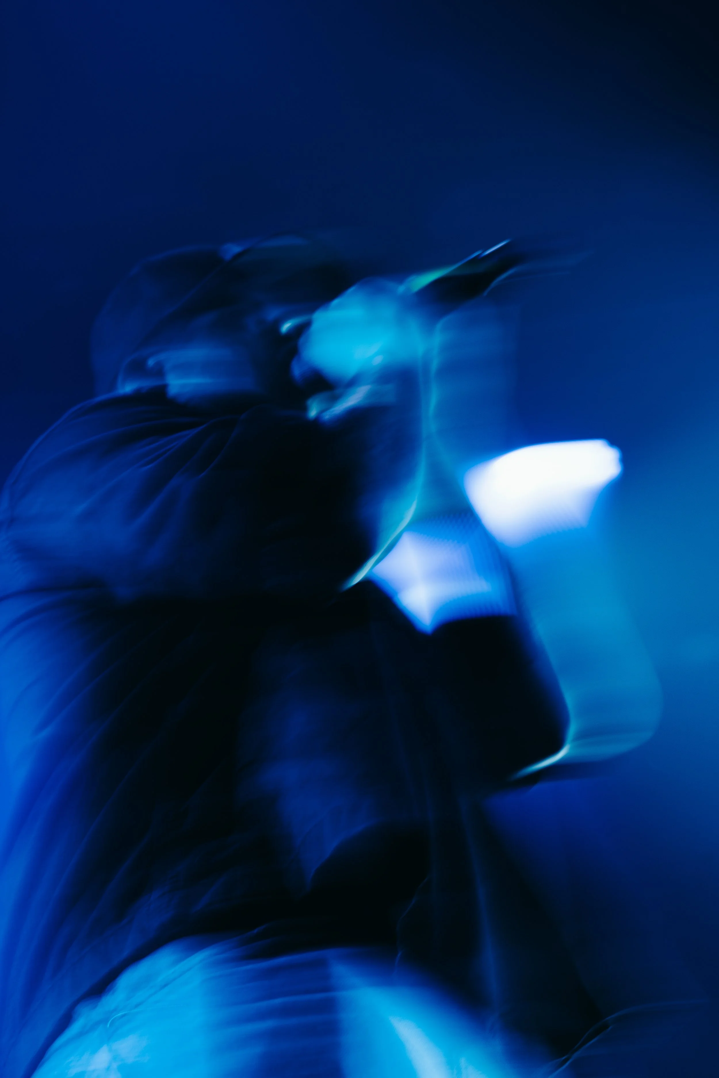 Une personne en mouvement dans un éclairage bleu, photo floue et abstraite.