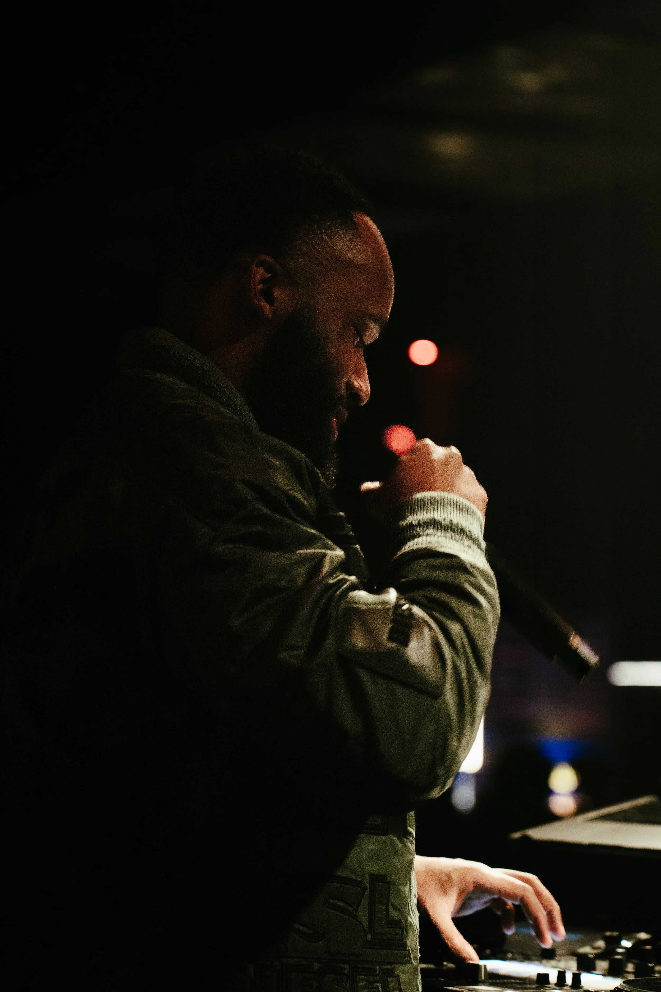 Un homme joue avec un microphone dans une pièce sombre.