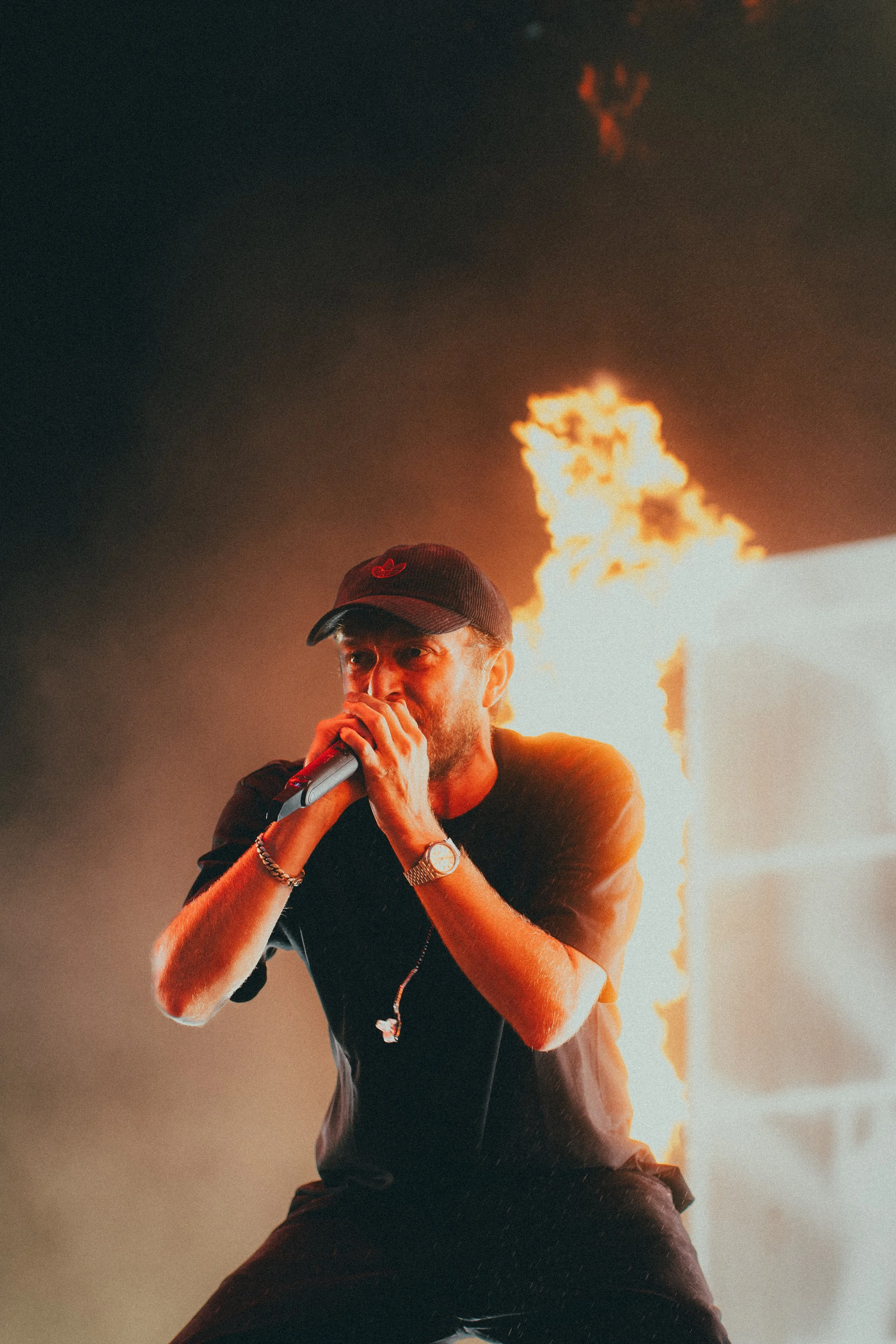 Un homme chantant avec un microphone, en direct, avec un feu en arrière-plan.