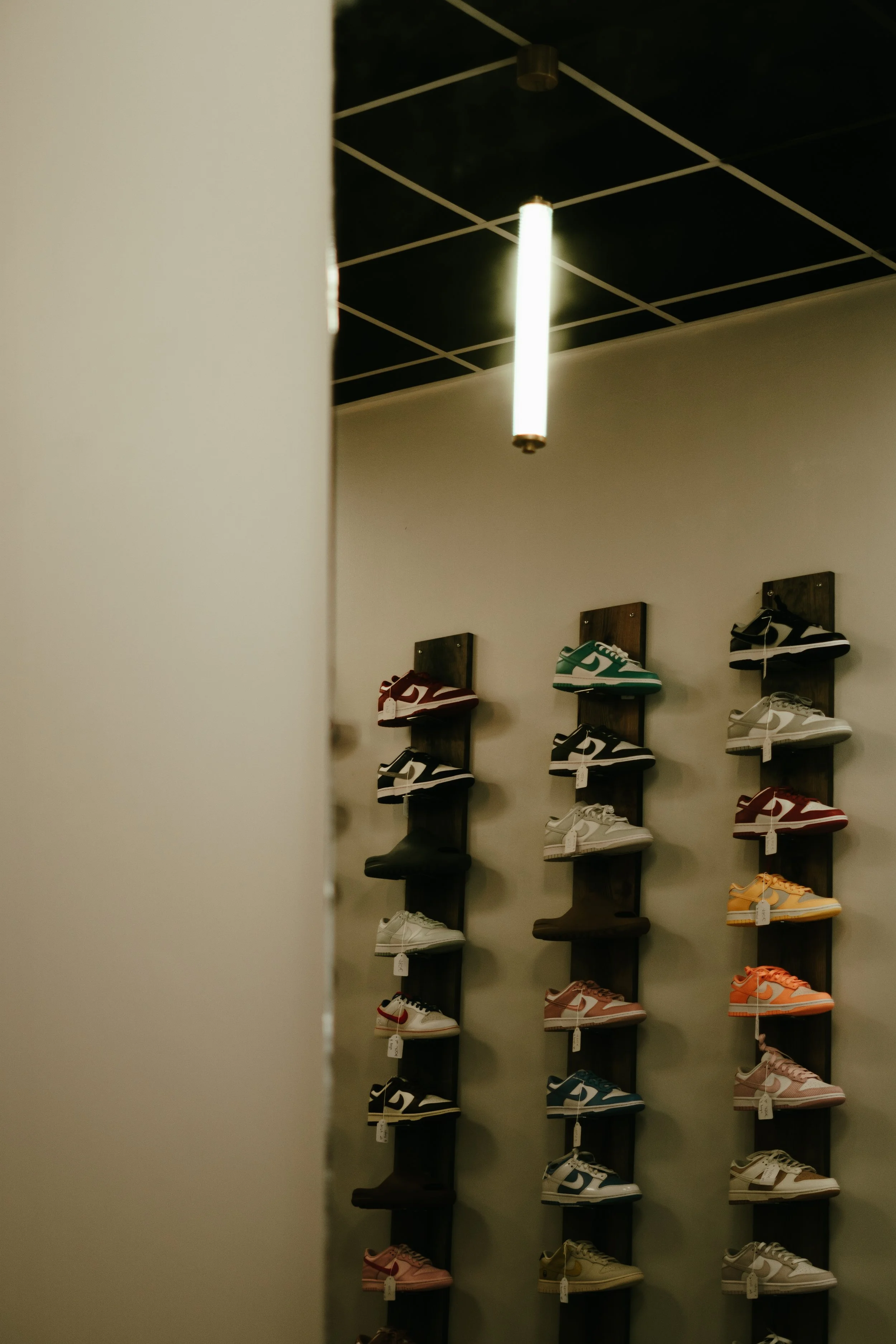 Exposition de baskets de différentes couleurs sur un mur dans un magasin de chaussures.