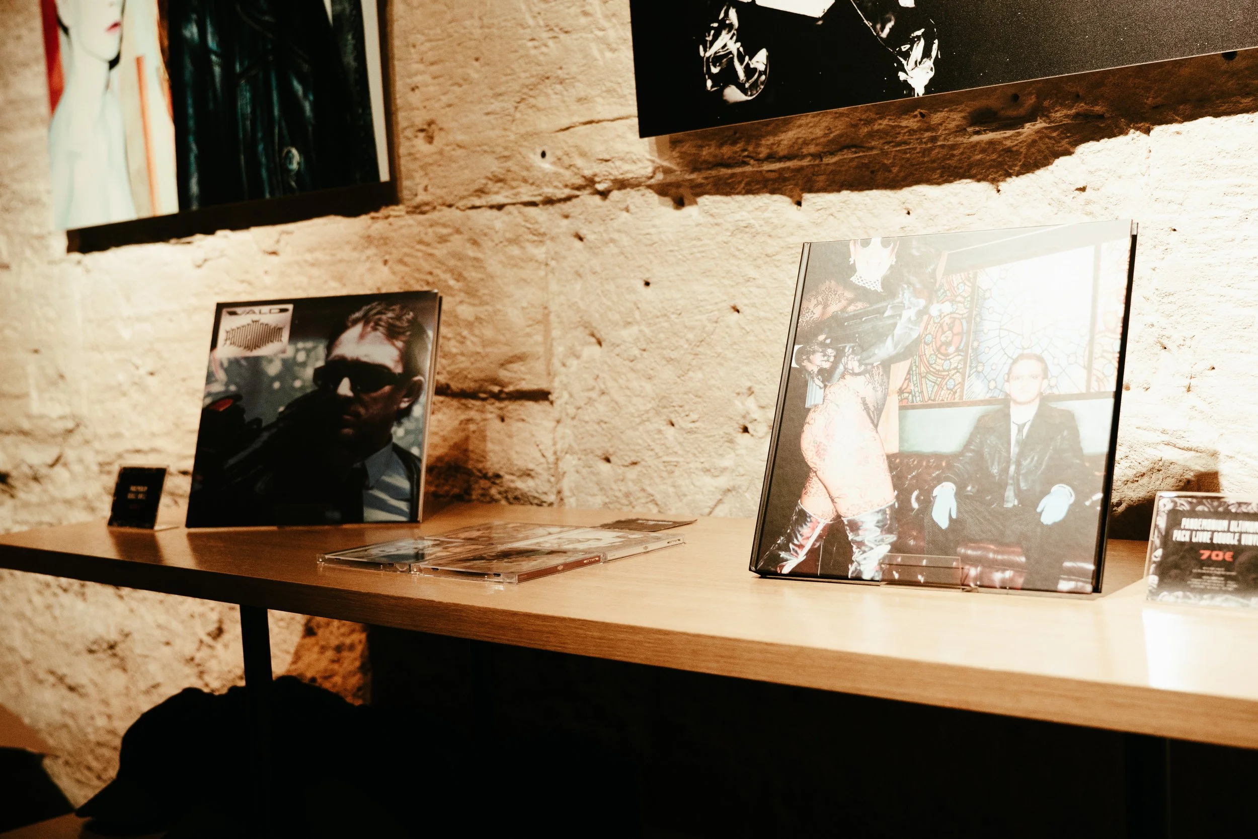 Photographies et affiches d'art exposées sur un mur en pierre dans une galerie ou un musée.