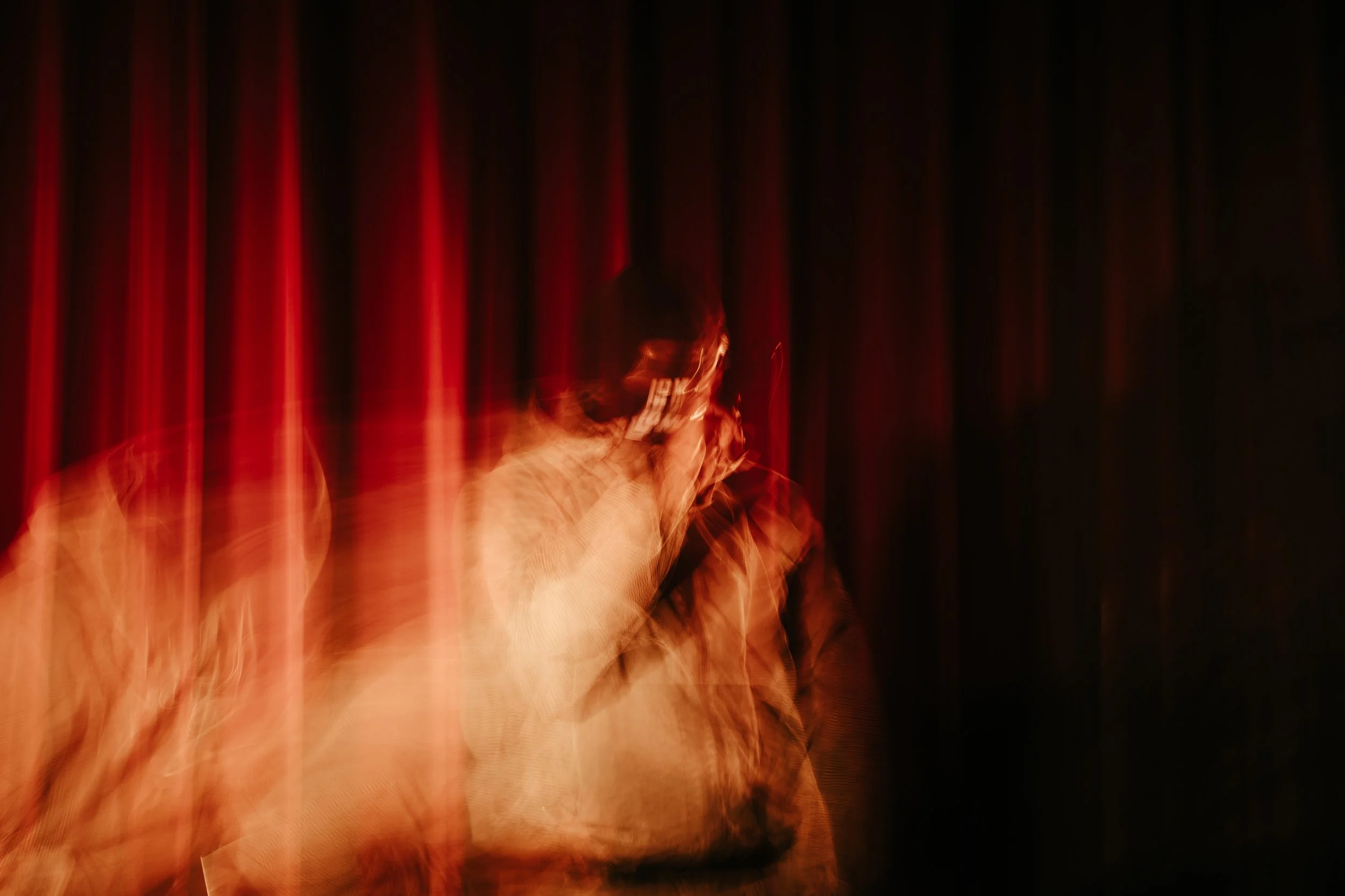 Personne parlant au téléphone, floue et mouvementée, avec des rideaux rouges en arrière-plan