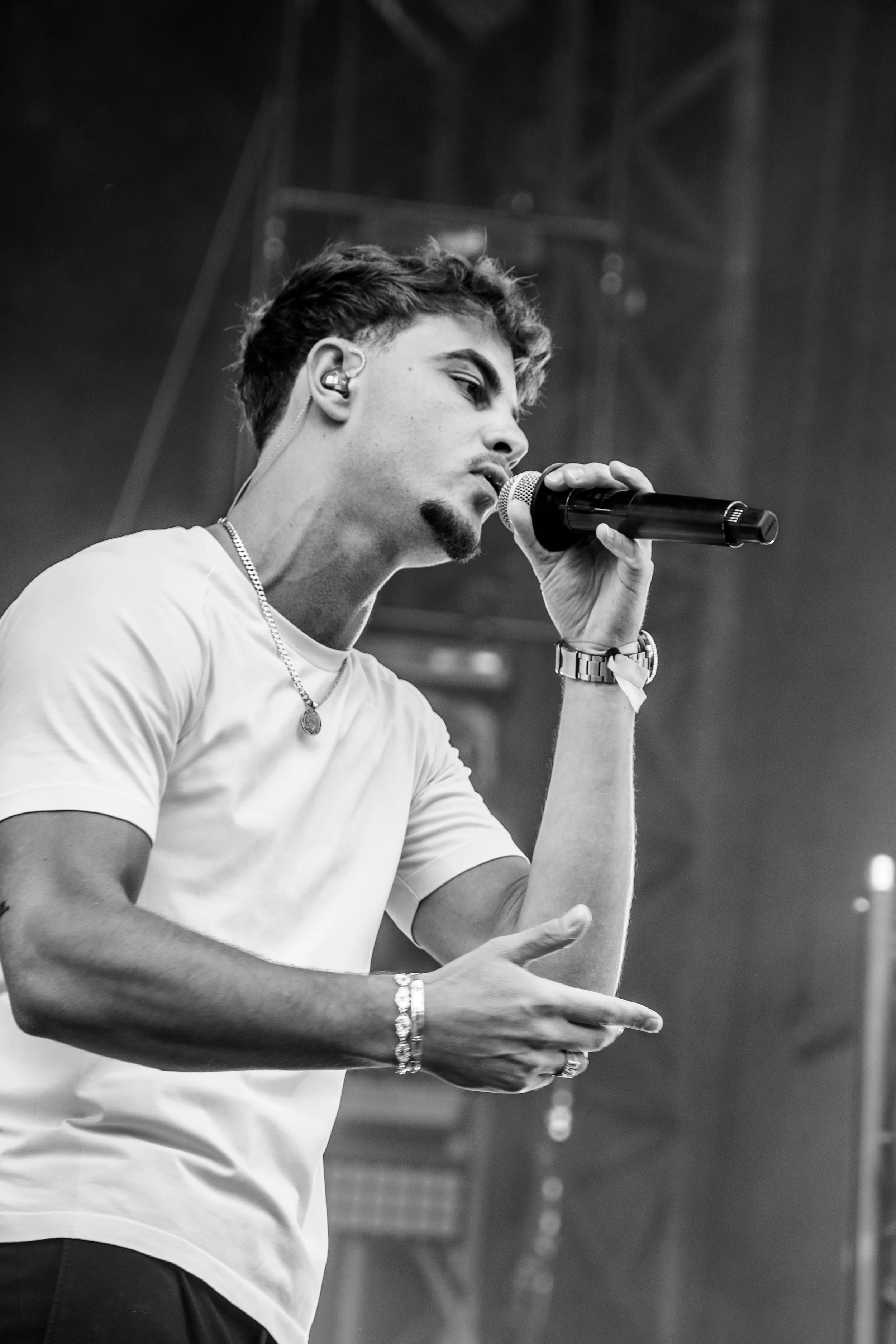 Un jeune homme chante dans un micro lors d'un concert, en noir et blanc.