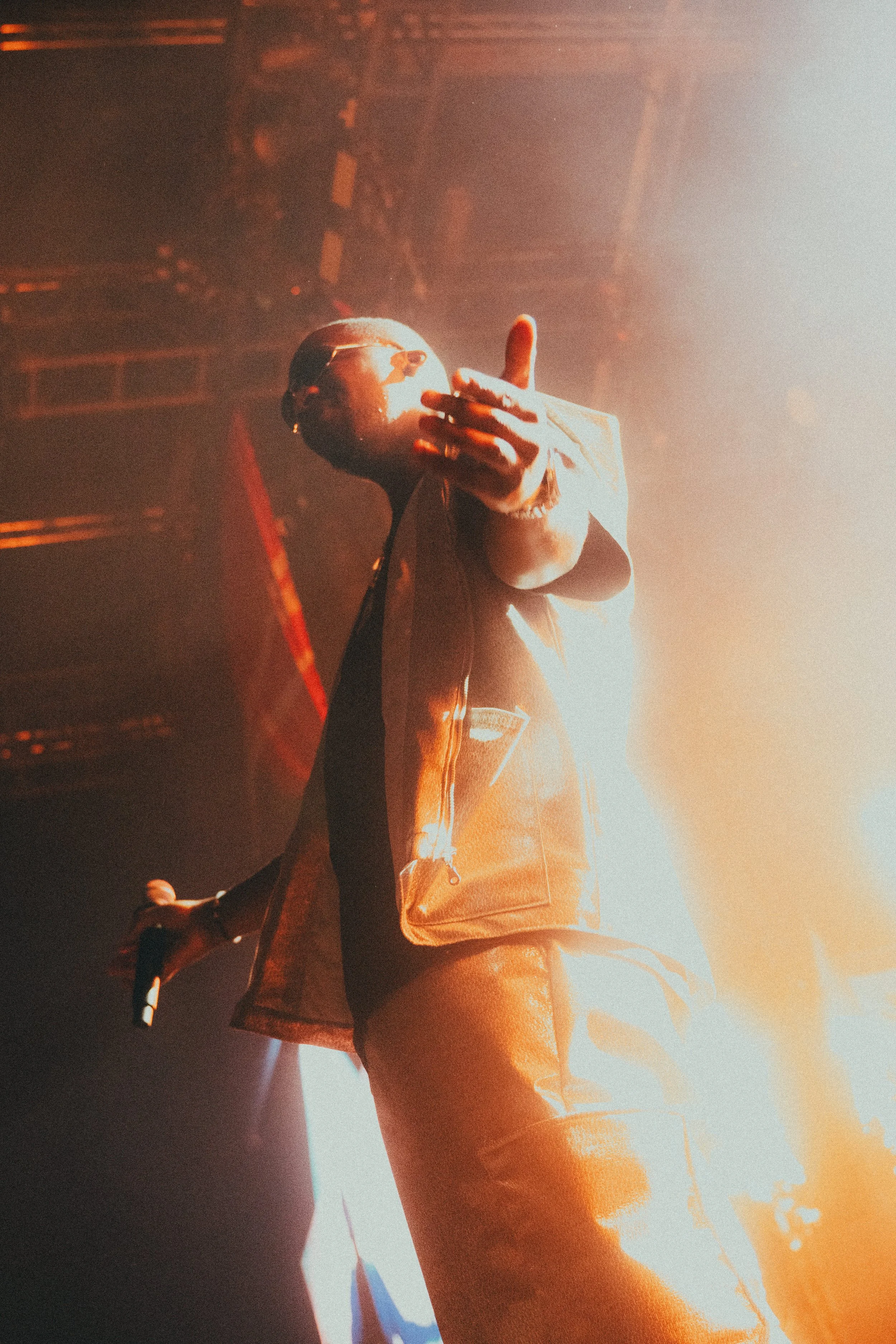 Un homme chante sur scène lors d'un concert, avec des lumières chaudes et une ambiance électrique.