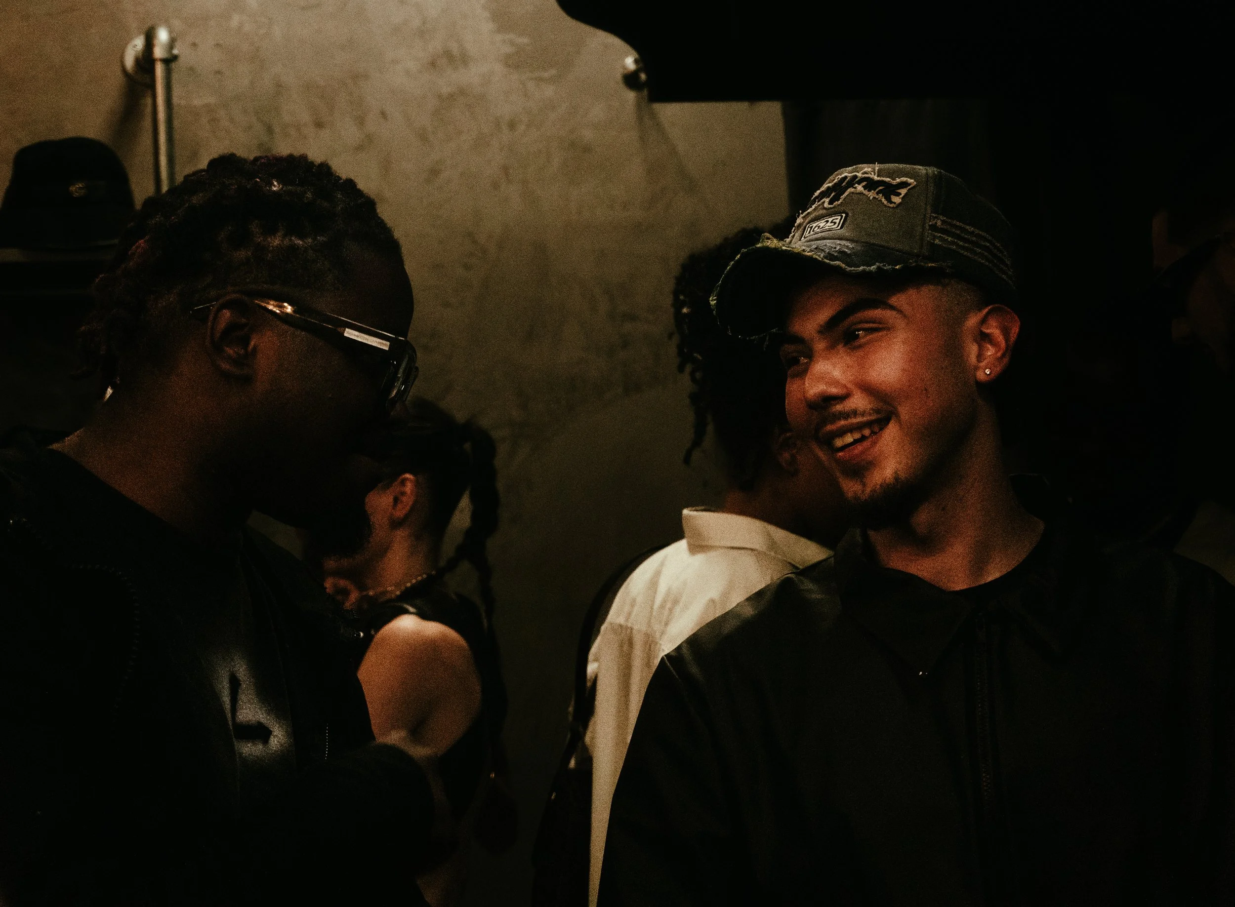 Jeunes adultes discutant et souriant dans un lieu sombre.