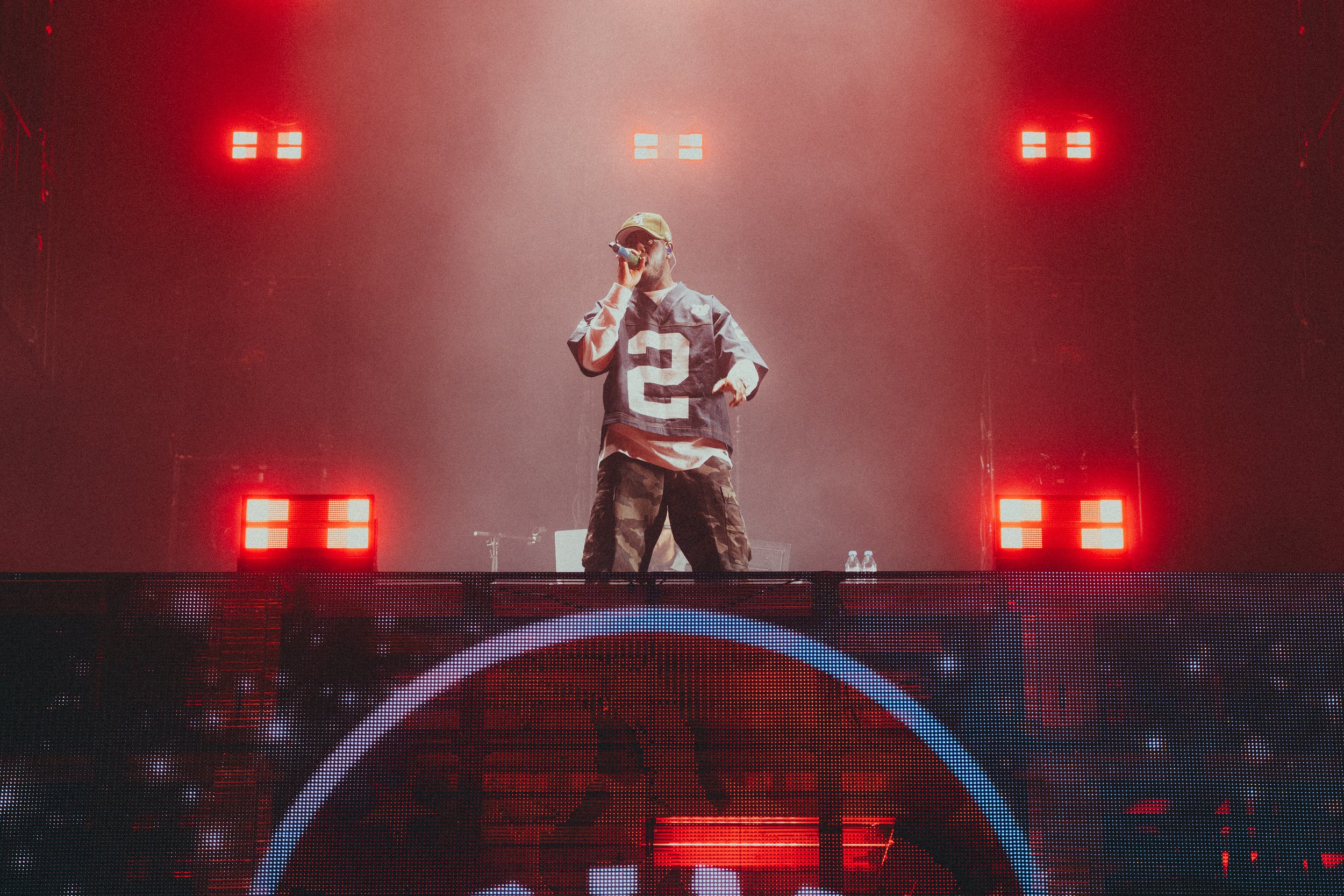 Un artiste de rue performe sur scène avec des lumières rouges en arrière-plan.