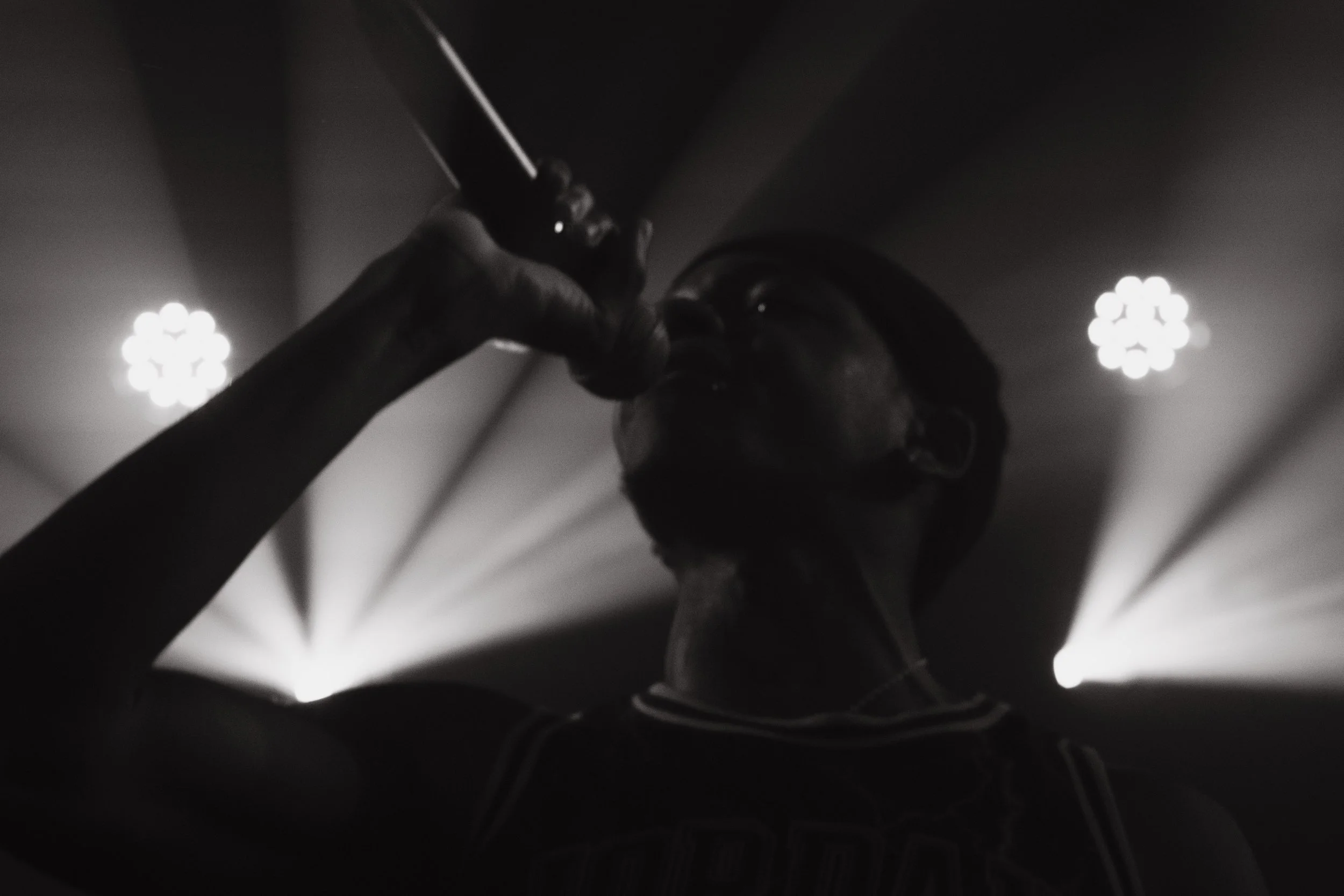 Une personne mangeant ou buvant quelque chose dans une pièce sombre, éclairée par des lumières en arrière-plan.