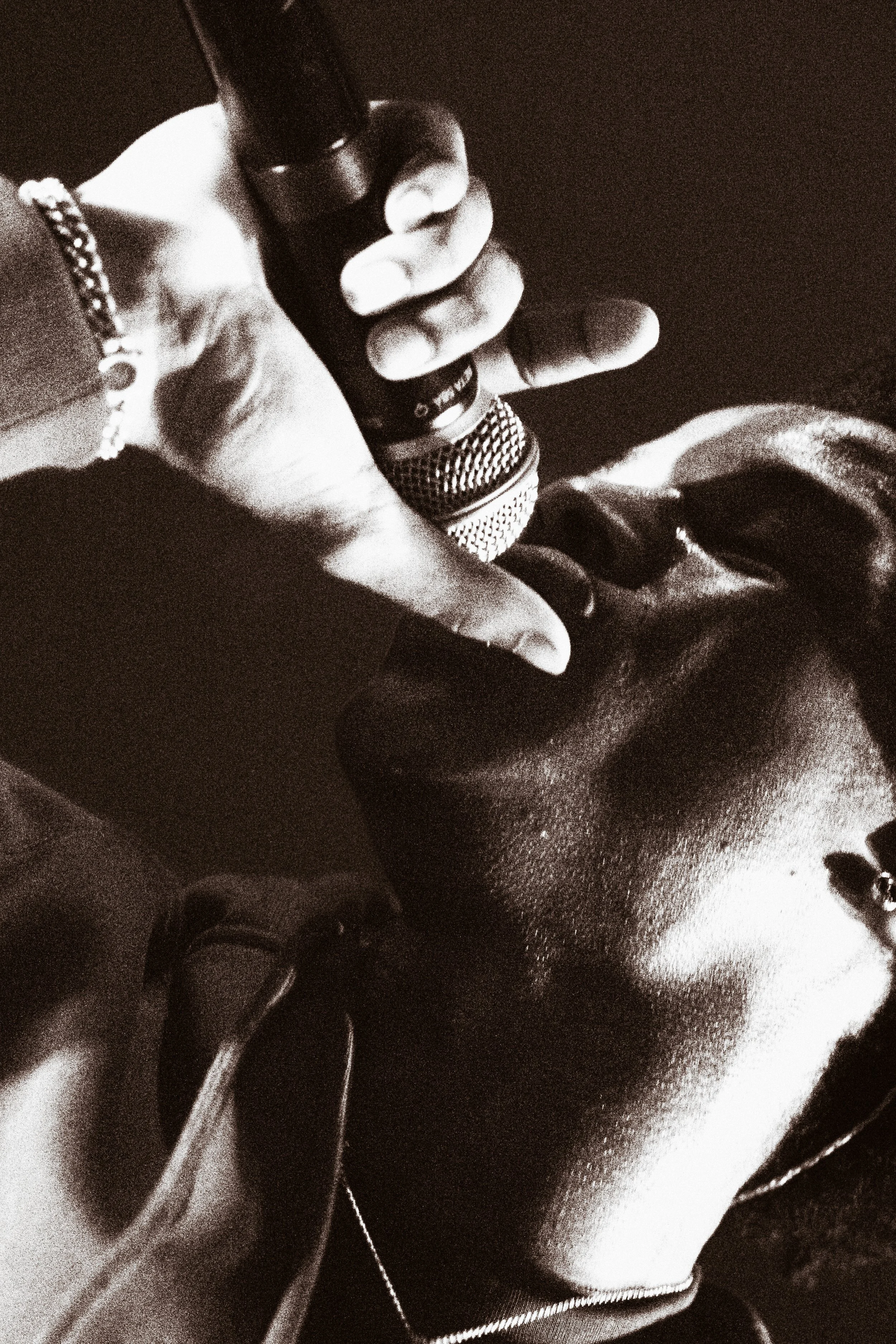 Une personne tenant un microphone, vue de profil, en noir et blanc.