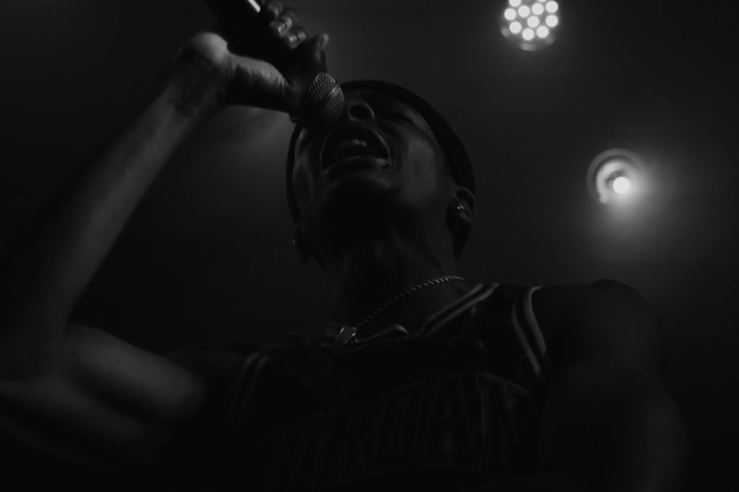 Une personne chantant dans un micro dans une ambiance sombre et intense.