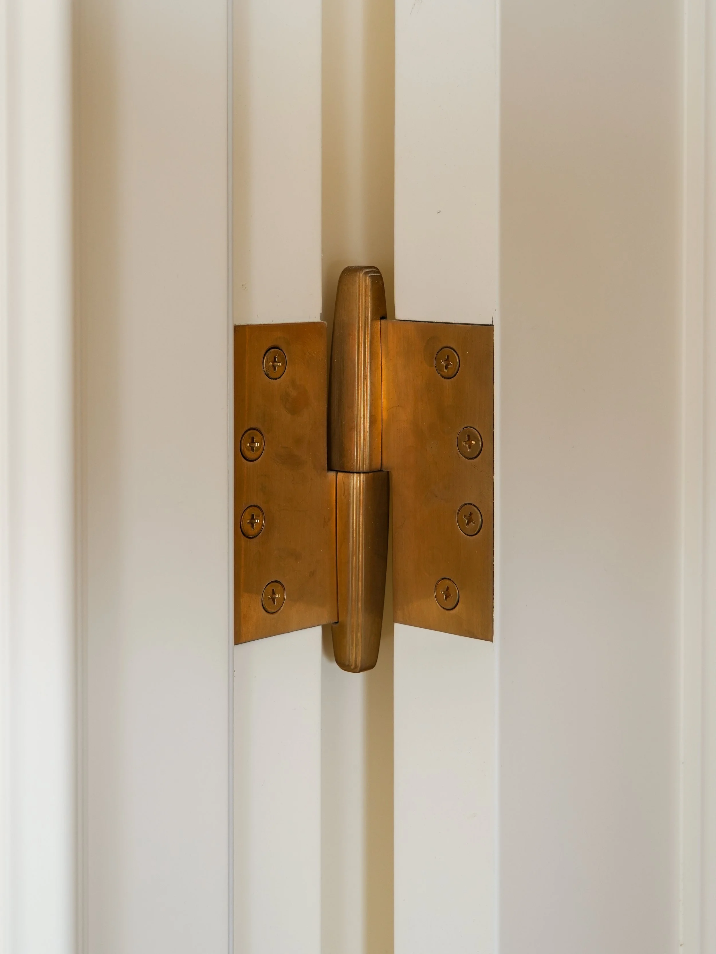 Close-up of a solid-brass architectural hinge with naturally developed light patina