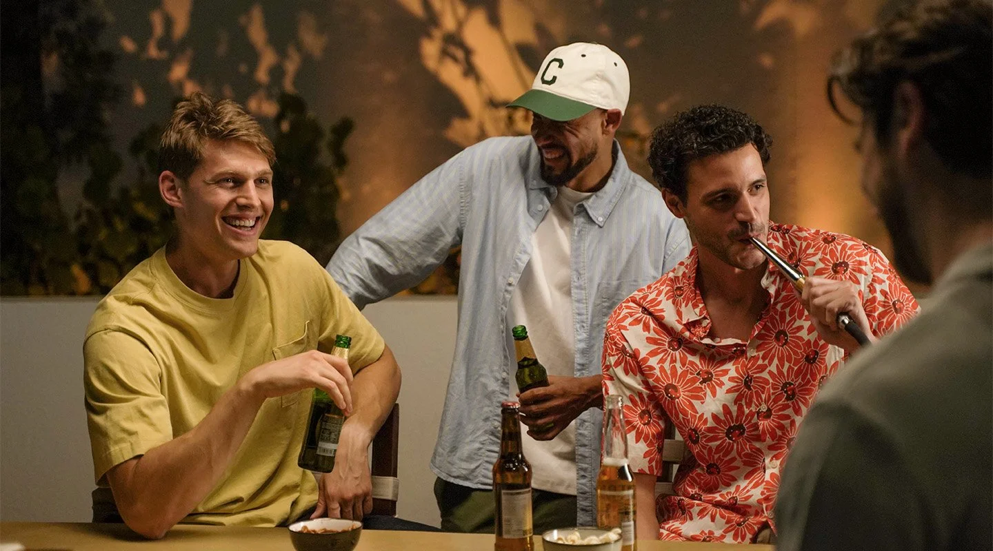 Group of friends laughing and socializing around a table during a shisha session, reflecting the communal nature of shisha culture.