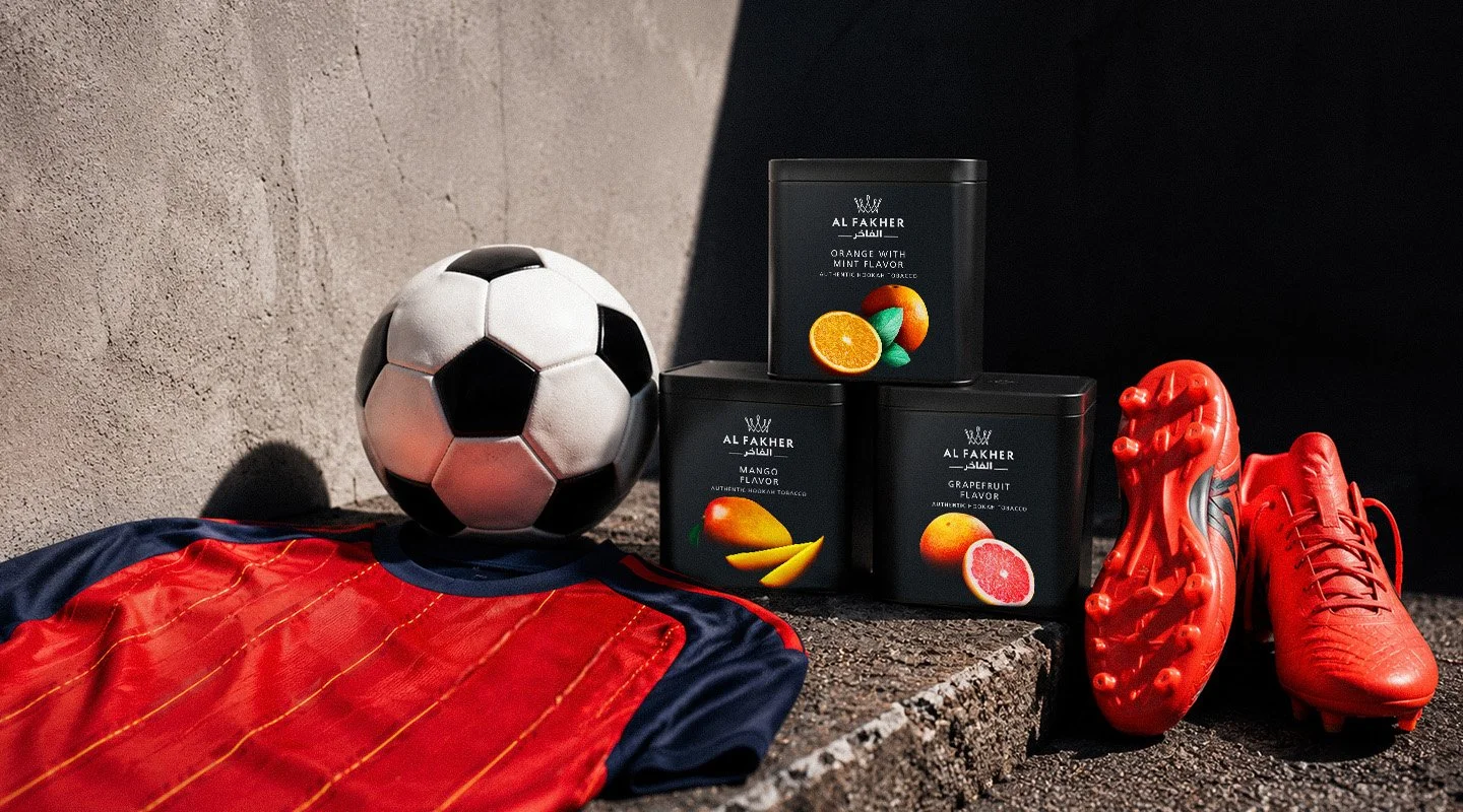 Al Fakher Orange with Mint, Mango and Grapefruit tubs displayed with a football jersey, ball and red boots.