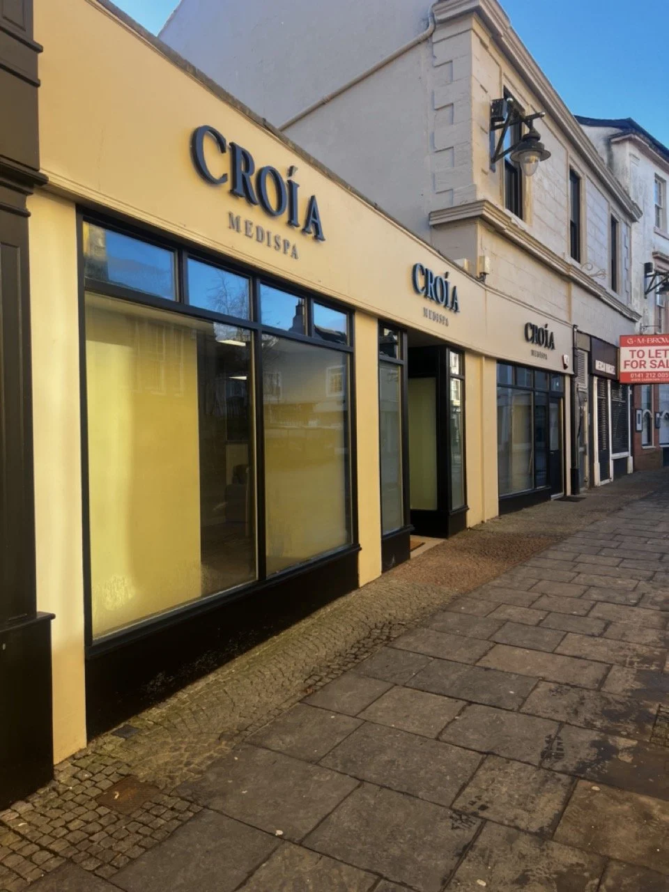 Sophisticated clinic storefront of Croia Medispa in Kilmarnock, Ayrshire  with large windows on Bank Street. The street is cobbled and has a quaint feel