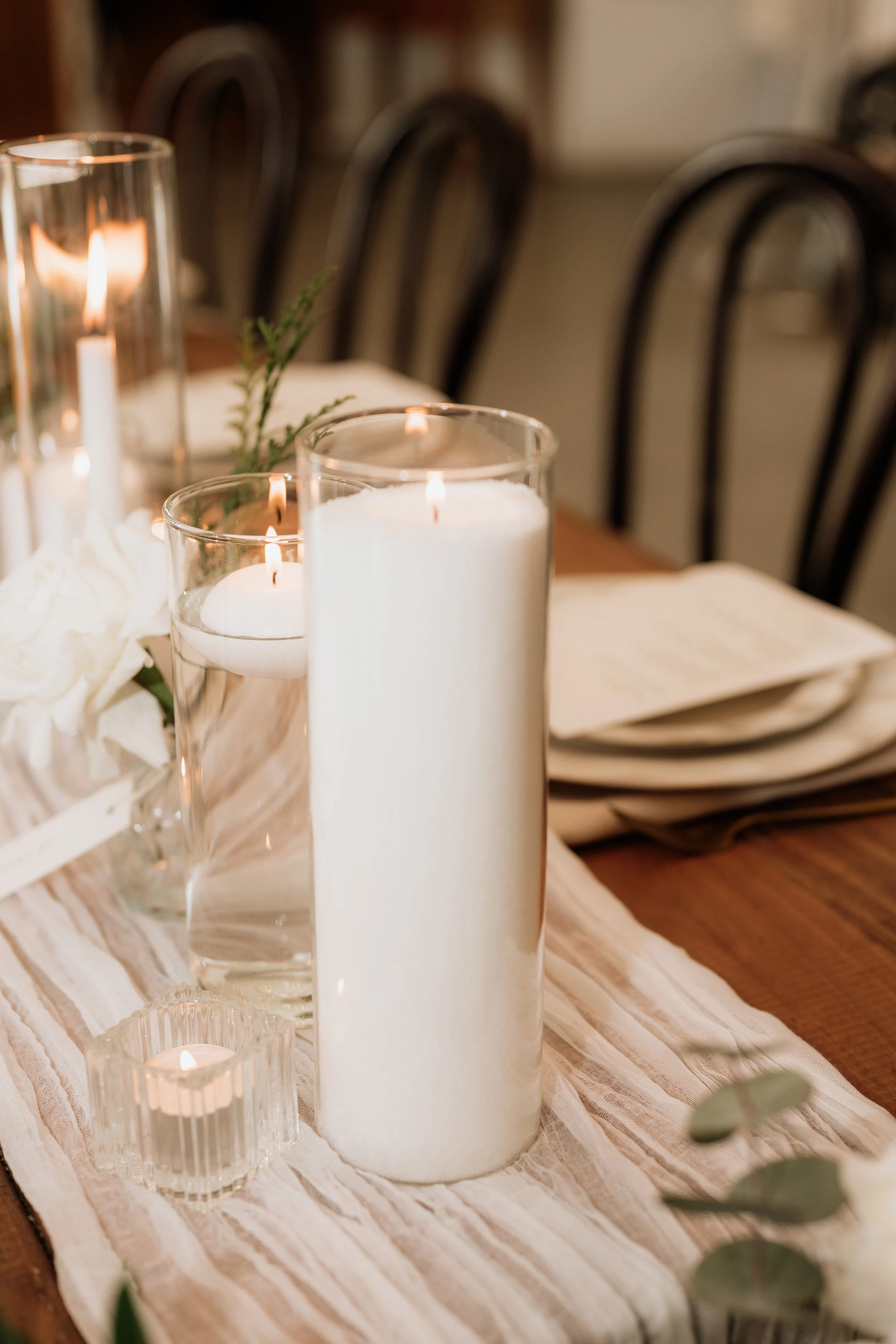 A dried flower arrangement in a white pot containing white hydrangea, cream palm fan, silver palm fan, beige bunny tails, white ming fern and a cream banksia in the centre