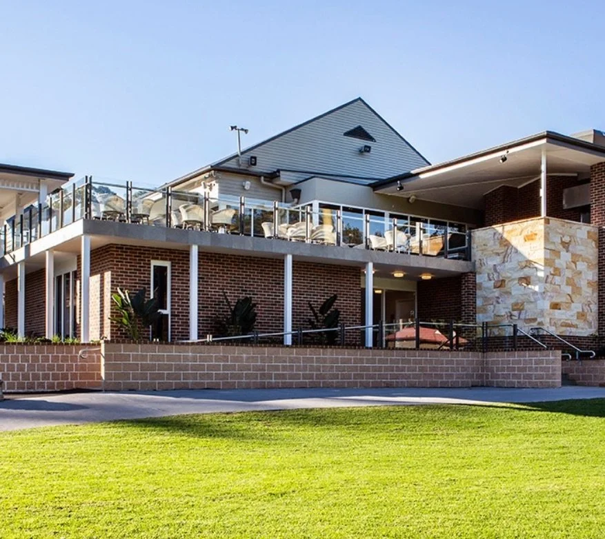 Modern brick building with a glass-railed balcony and green lawn