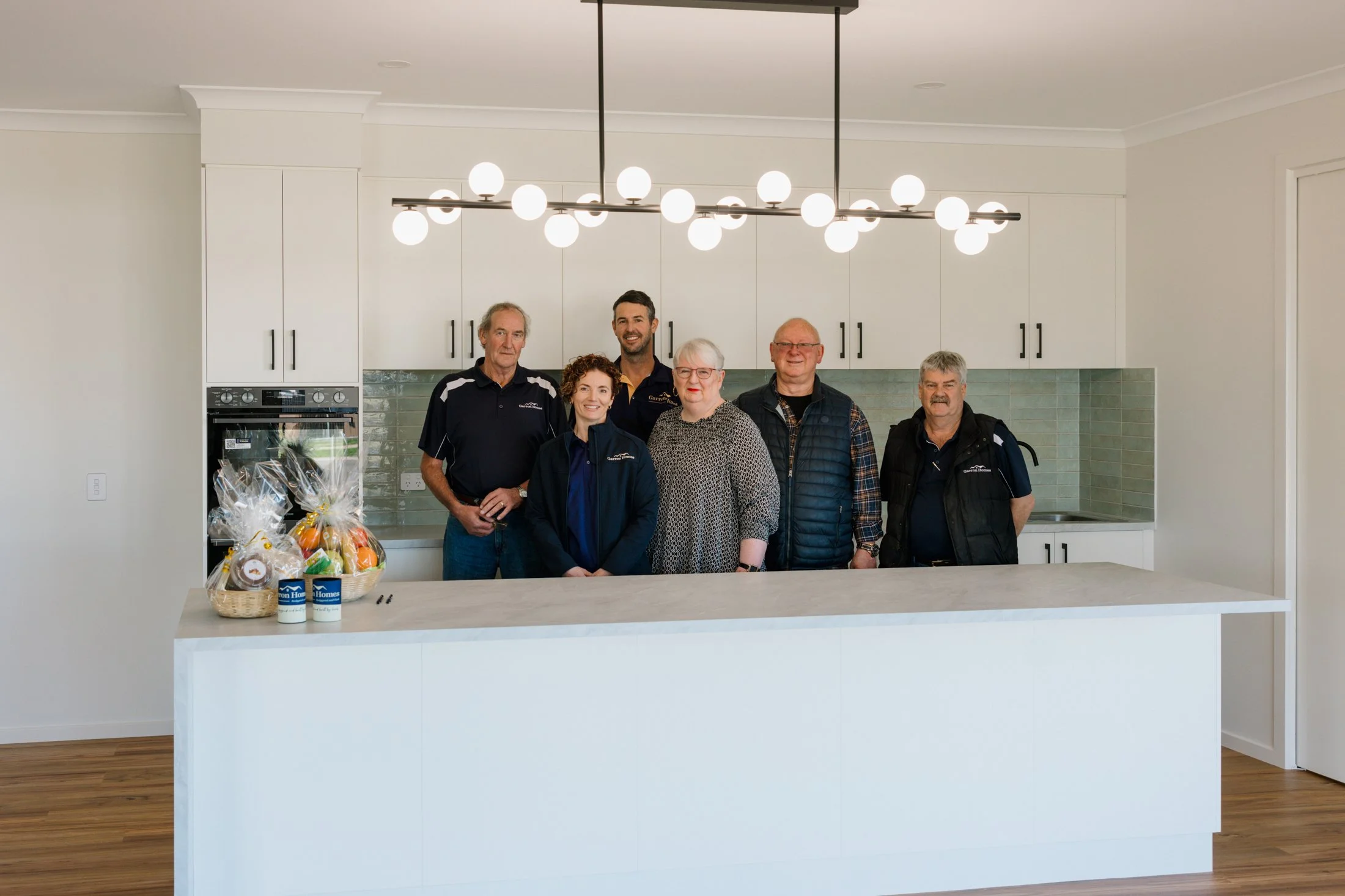 Garron Homes Team Photo in modern new kitchen with feature lights above