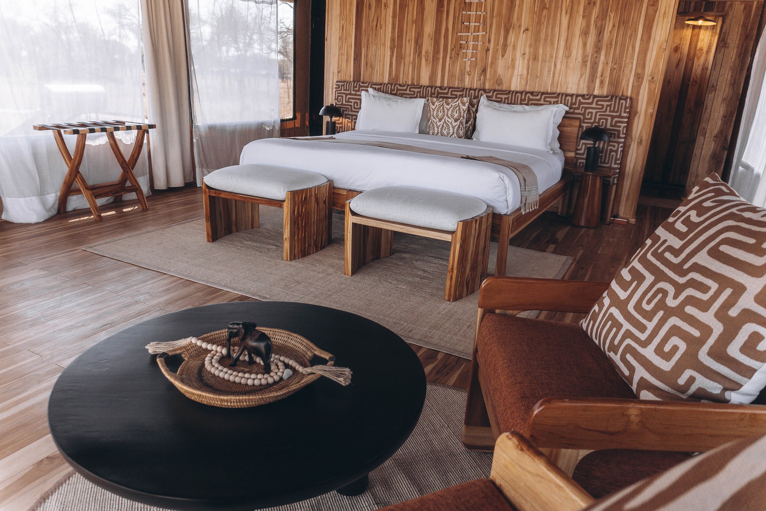 Luxury safari tent exterior with wooden deck, chairs, and scenic views, offering an exclusive African glamping experience.