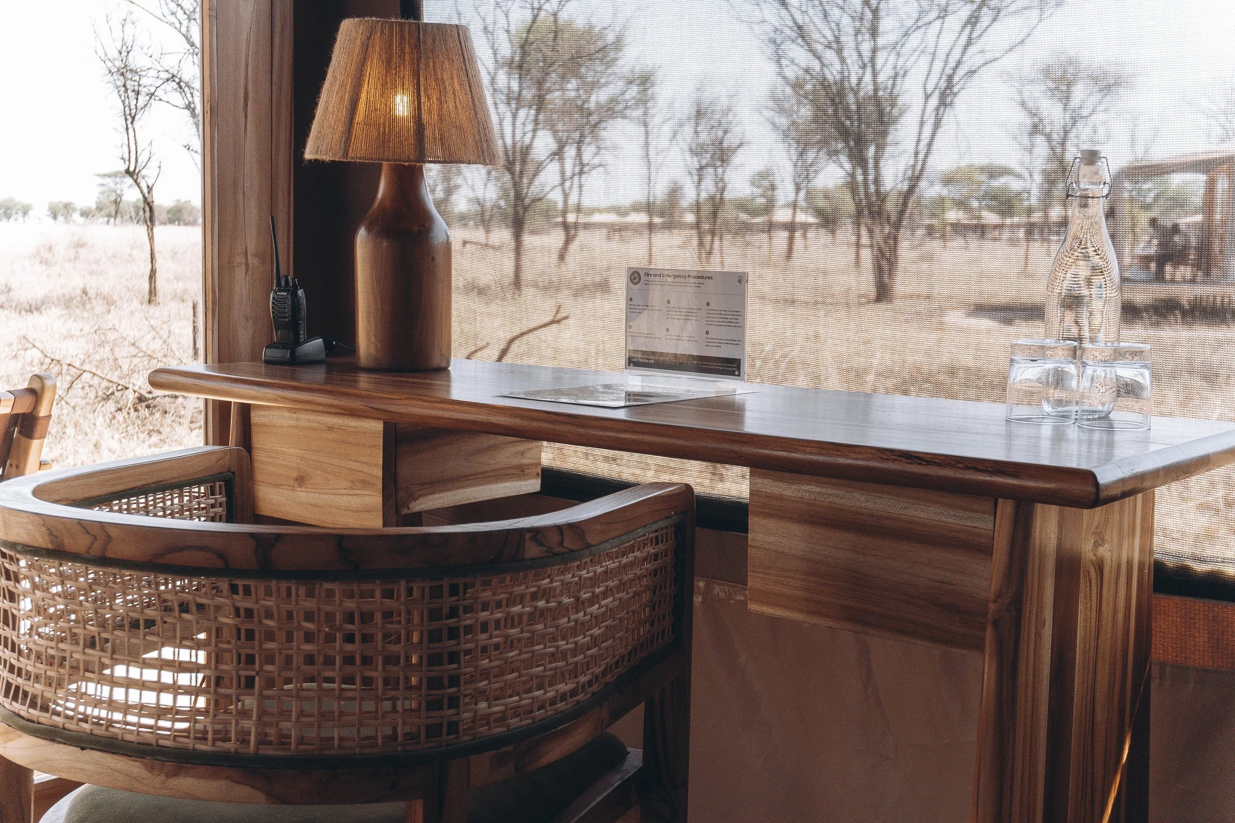 Luxury safari tent bedroom with African print pillows, wooden furniture, and natural decor for an elegant wilderness retreat.