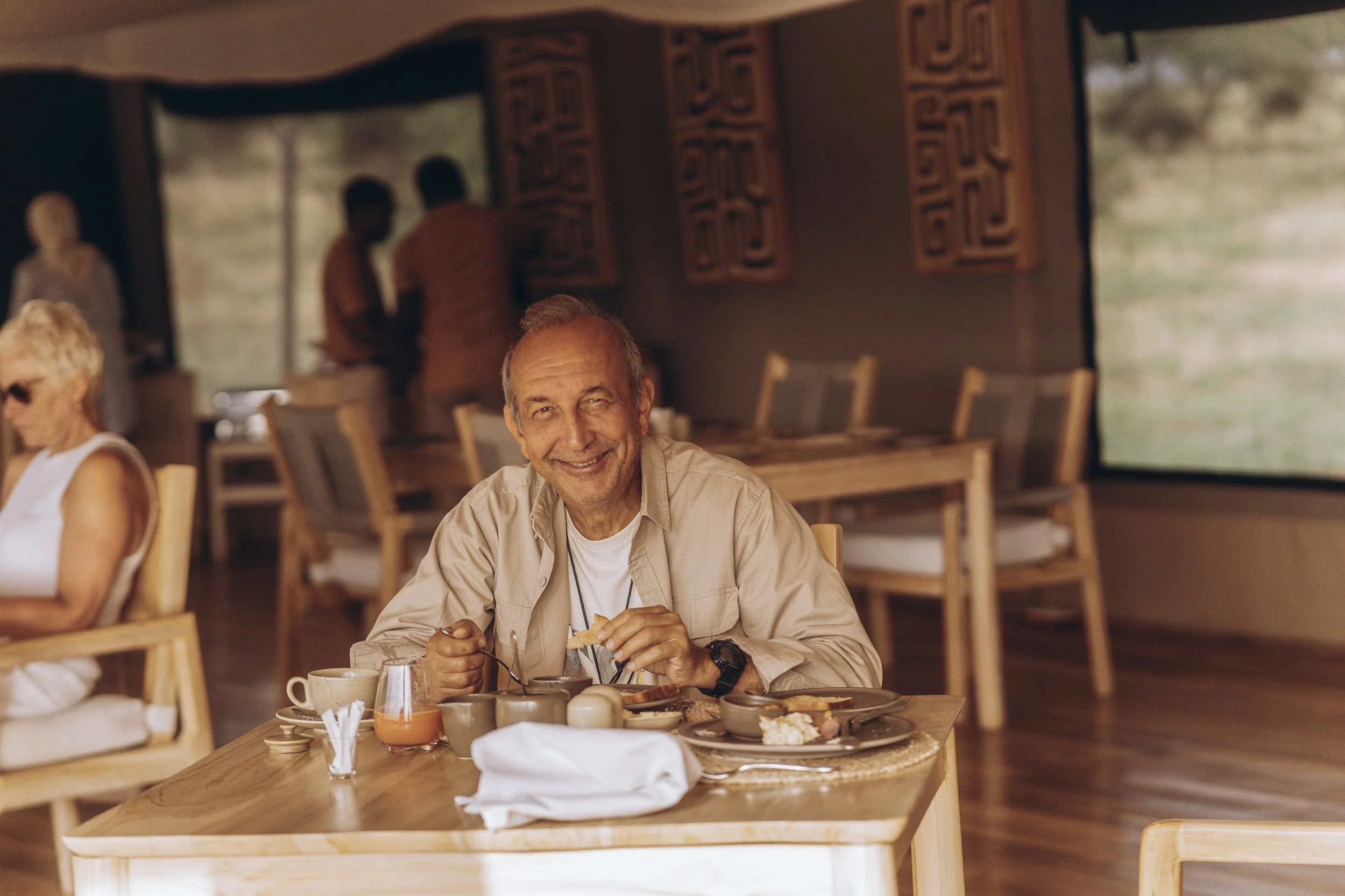 Friendly safari lodge staff welcoming guests with fresh towels inside a luxury tented suite, showcasing premium hospitality service.