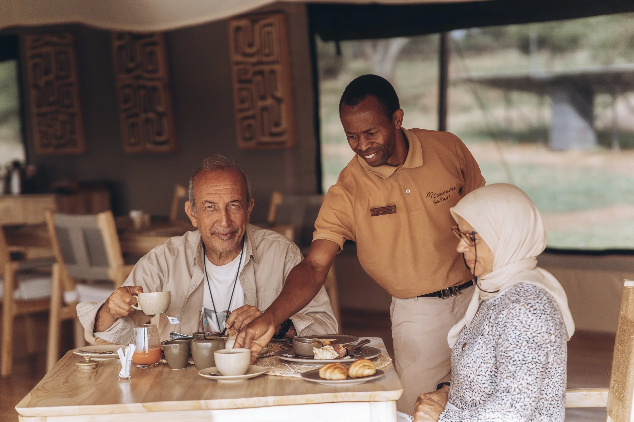 Safari lodge barista preparing fresh coffee with espresso machine, offering guests a luxury glamping experience in the African bush.