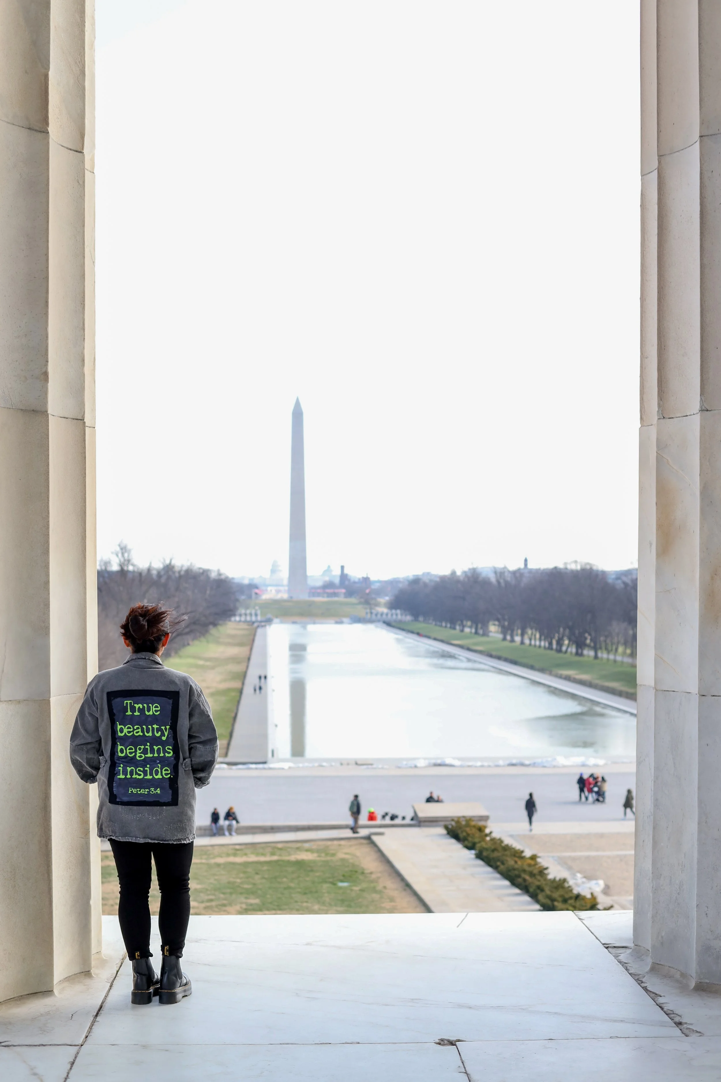 Person standing in the Lincoln Memorial, looking out at the reflecting pool and the Washington Monument in Washington, D.C.