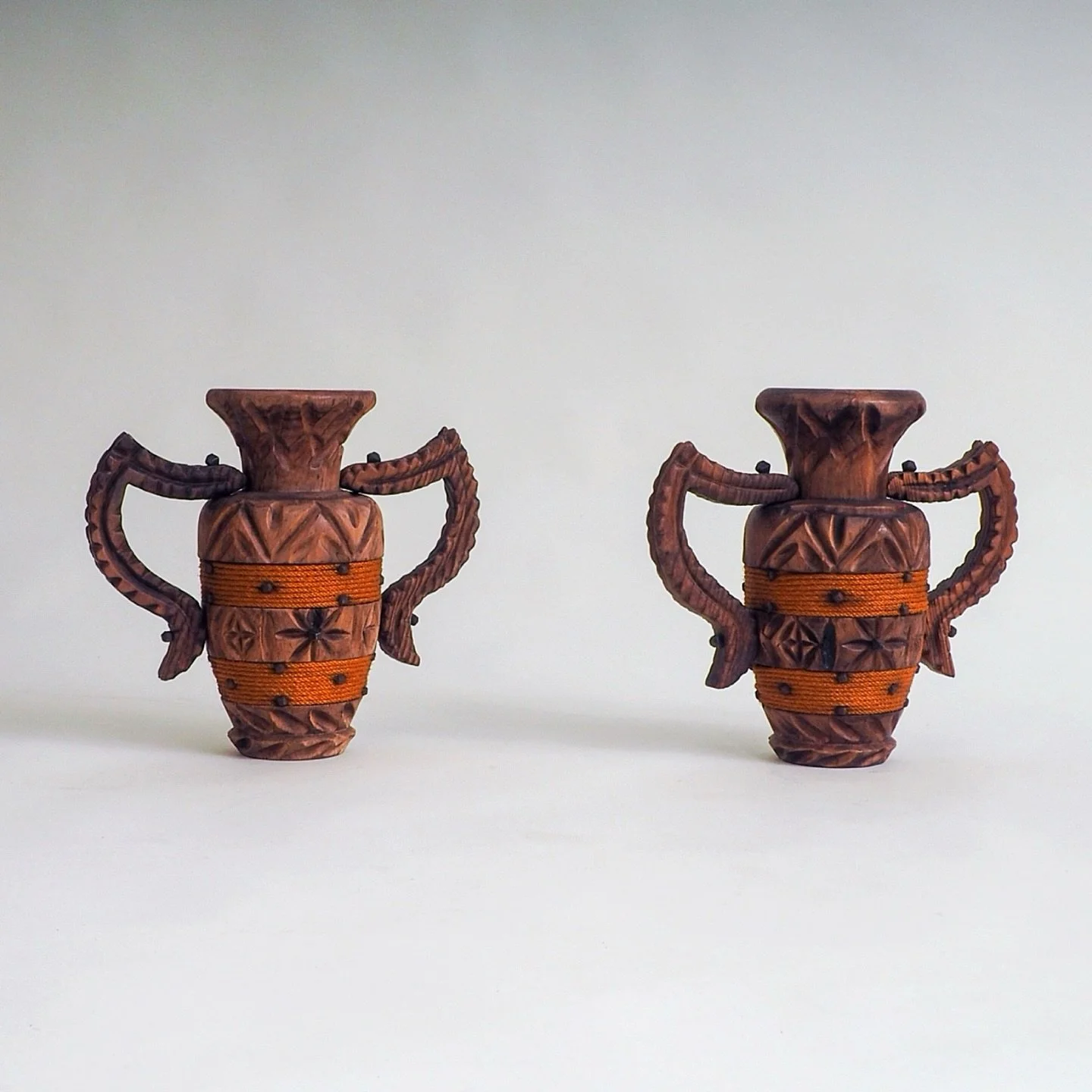 Set of 2 Spanish Brutalist Vases

Decorative set of 2 hand carved wooden vases. The carved wood alternates well with the deep orange wrapped cord. Great pair to decorate a long side board. These vases were made in Spain in the 1970&rsquo;s and are in