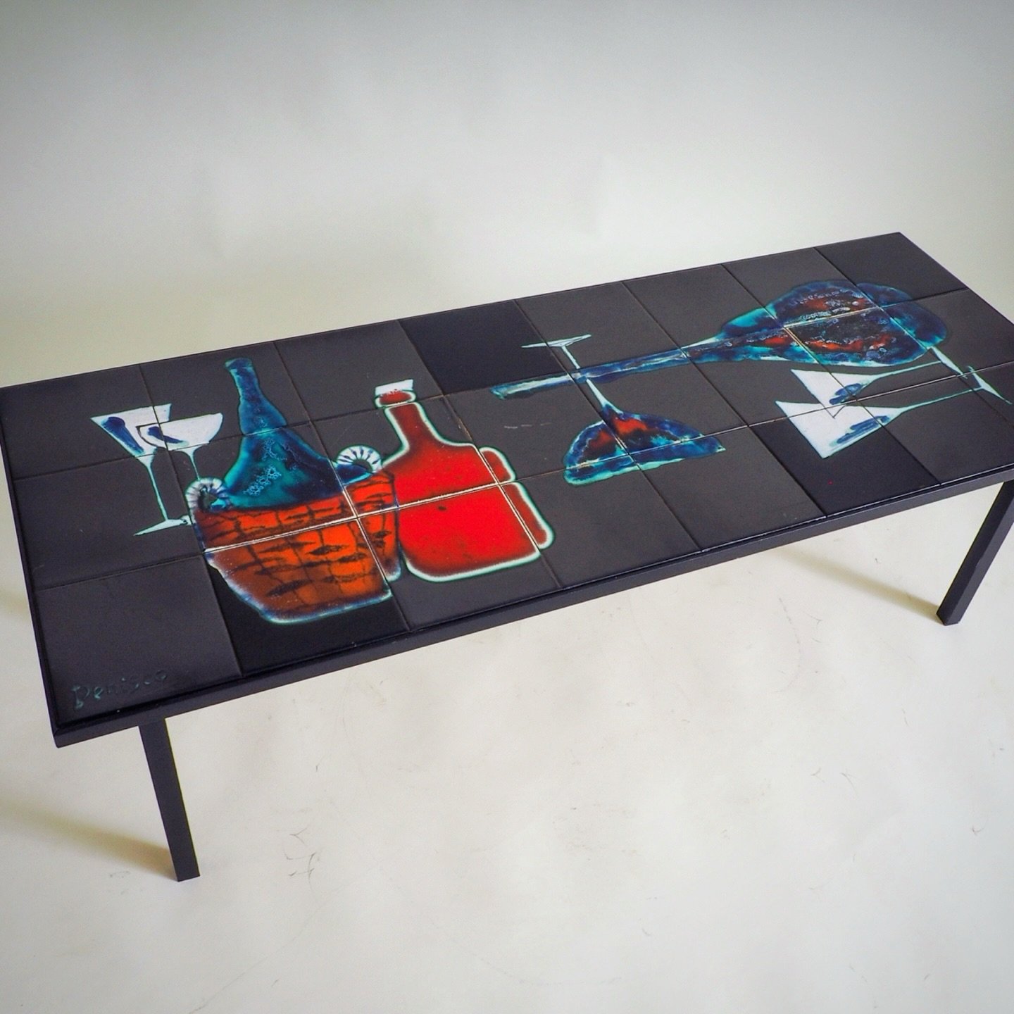 Mid-Century Modern &ldquo;Cocktail Hour&rdquo; Tile Coffee Table by Antonio Denisco (1960s)

This striking Mid-Century Modern coffee table is a signature piece by the renowned artist Antonio Denisco. The rectangular tabletop features a series of indi