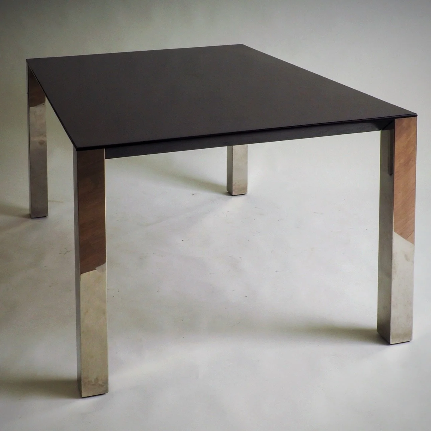 Dining Table by Giovanni Offredi for Saporiti

The table is characterized by a stark yet luxurious contrast between its two primary materials. The substantial tabletop is crafted from richly toned rosewood, featuring a dark, smooth finish. Supporting