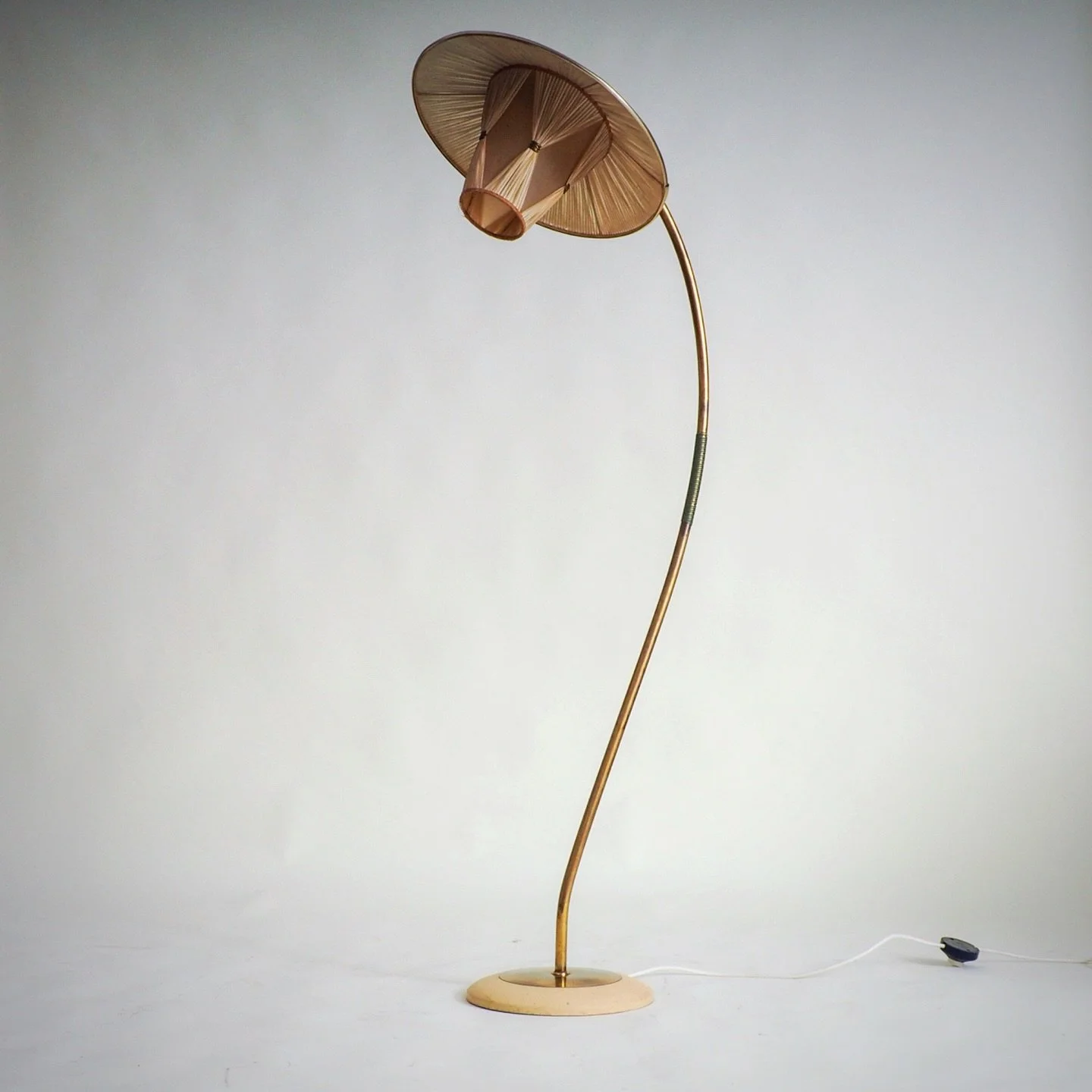 50s Floorlamp with Pleated Shade

This elegant Mid-Century Modern floor lamp features a gracefully curved brass stem, creating a light, sculptural silhouette. The lamp is crowned by a unique, layered textile shade, likely pleated, which casts a soft,