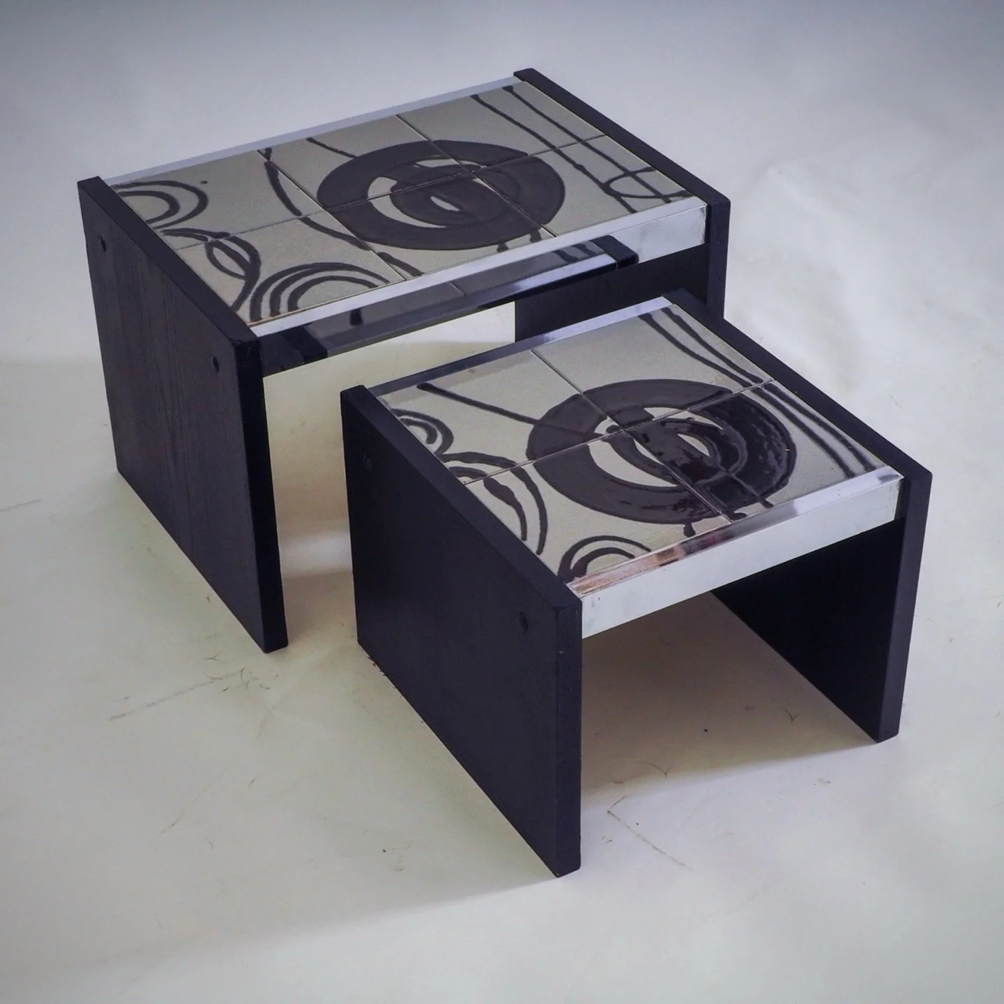 Set of 2 Tiled Nesting Side Tables

These tables are crafted with a sleek chrome frame and black wooden legs, complemented by a striking grey ceramic tile top that features an abstract pattern. 

Dimensions Large : W 50 x D 34 x H 32 / Small : W 39 x