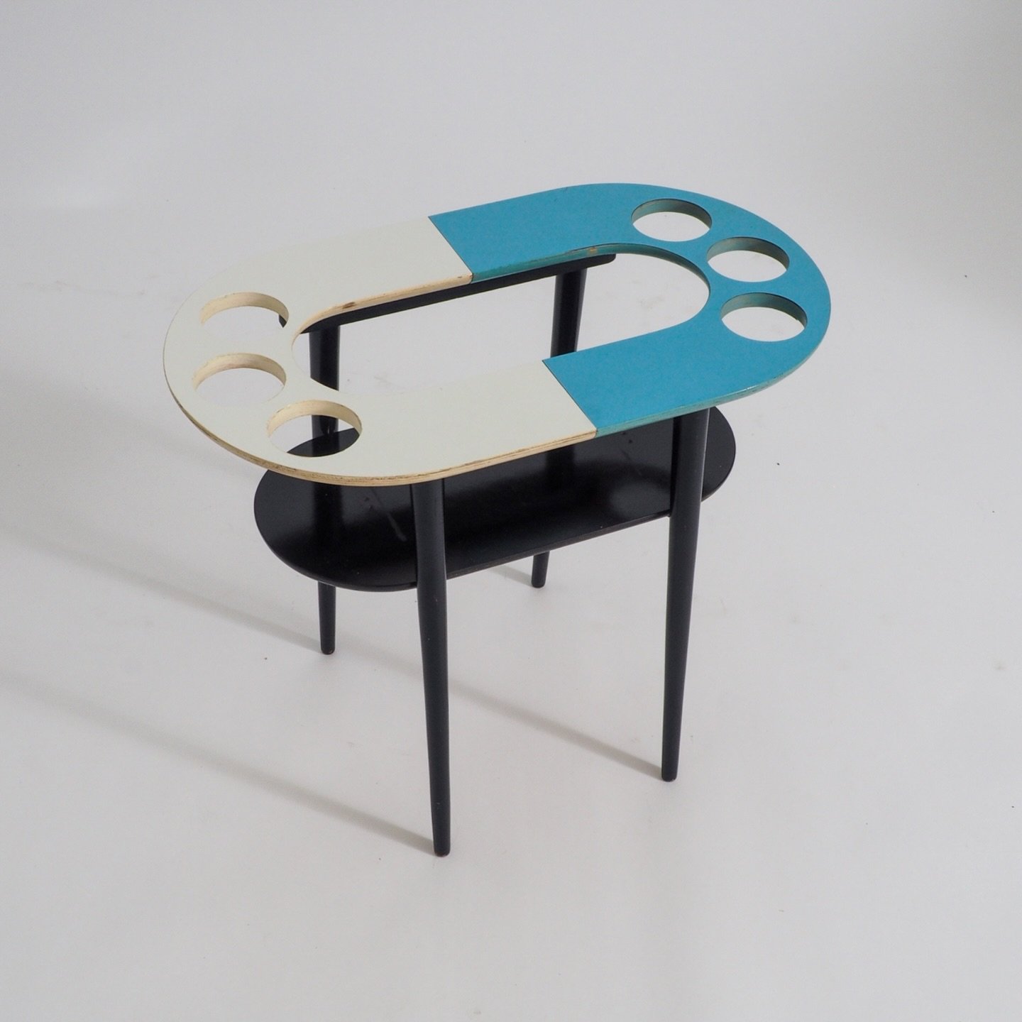 50s Plant Table, Side Table 

This charming and quirky 1950s side table has a unique design, featuring a striking blue and white top with circular cutouts, makes it an ideal plant table, an accent piece or even a mini bar table. 

The black wooden le