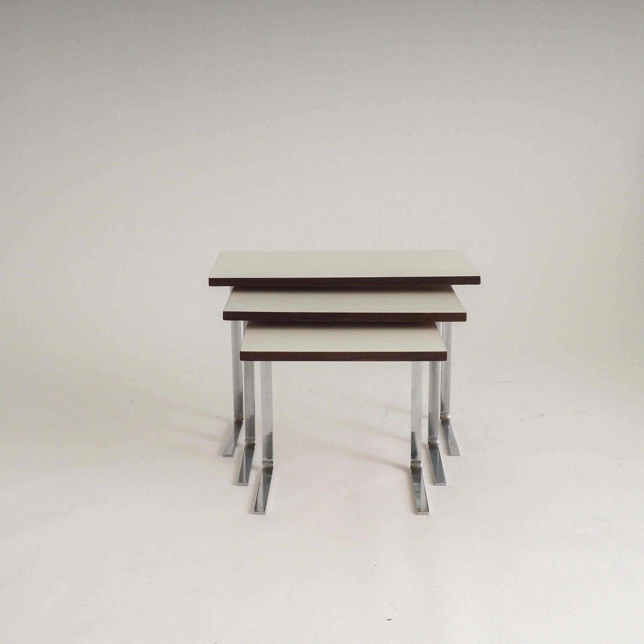 (SOLD) but too good not to share

Set of 3 Minimalistic Nesting Side Tables

Sleek set of three Mid-Century Modern nesting tables. Each table features a clean, white laminate top finished with a sophisticated dark wood-effect edge. The striking chrom