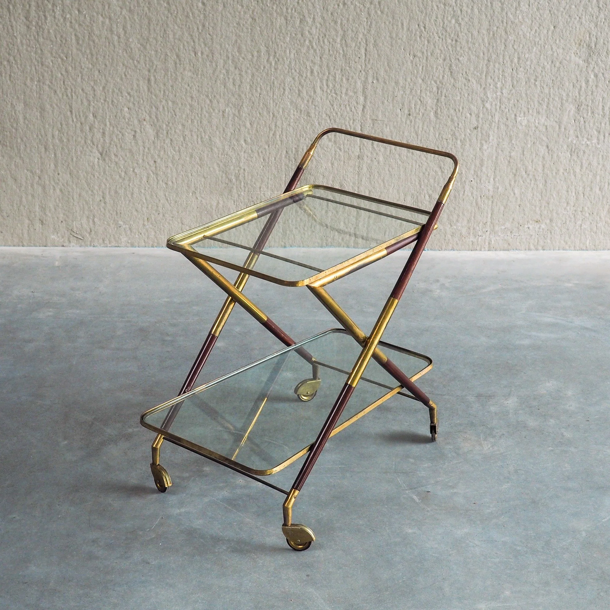 1950s Italian Bar Trolley, Attributed to Cesare Lacca

This 1950s Italian bar trolley exemplifies the elegant, dynamic lines characteristic of mid-century Italian design. Crafted with an expressive X-frame structure, it harmonizes rich dark wood acce