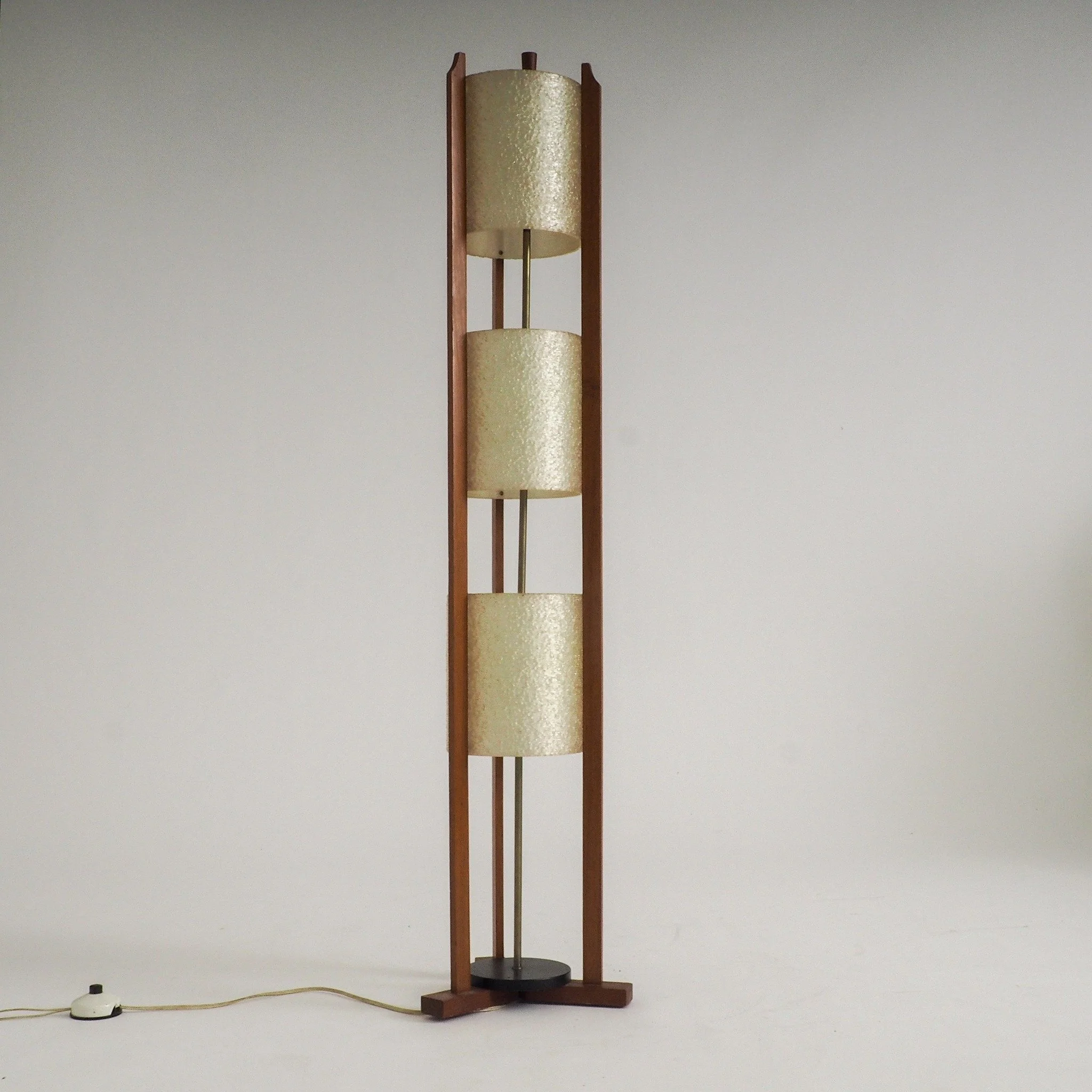 Mid-Century Modern 3-Tier Fiberglass &amp; Wood Floor Lamp

Timeless Mid-Century warmth with this striking 1950s architectural floor lamp. Crafted with an open-frame warm teak structure, a solid weighted black base, and a central brass stem, this pie