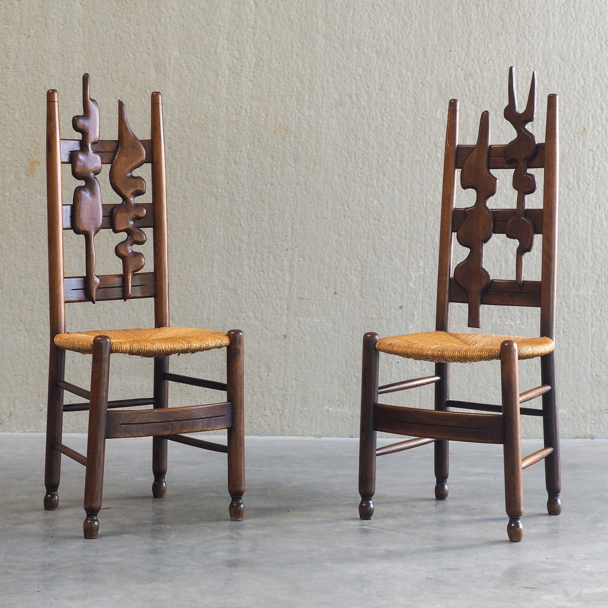 2 Sculptural Brutalist High-Back Chairs

An extraordinary pair of mid-century high-back chairs that bridge the line between functional furniture and fine art. These chairs feature striking studio-carved biomorphic splats integrated into a classic lad