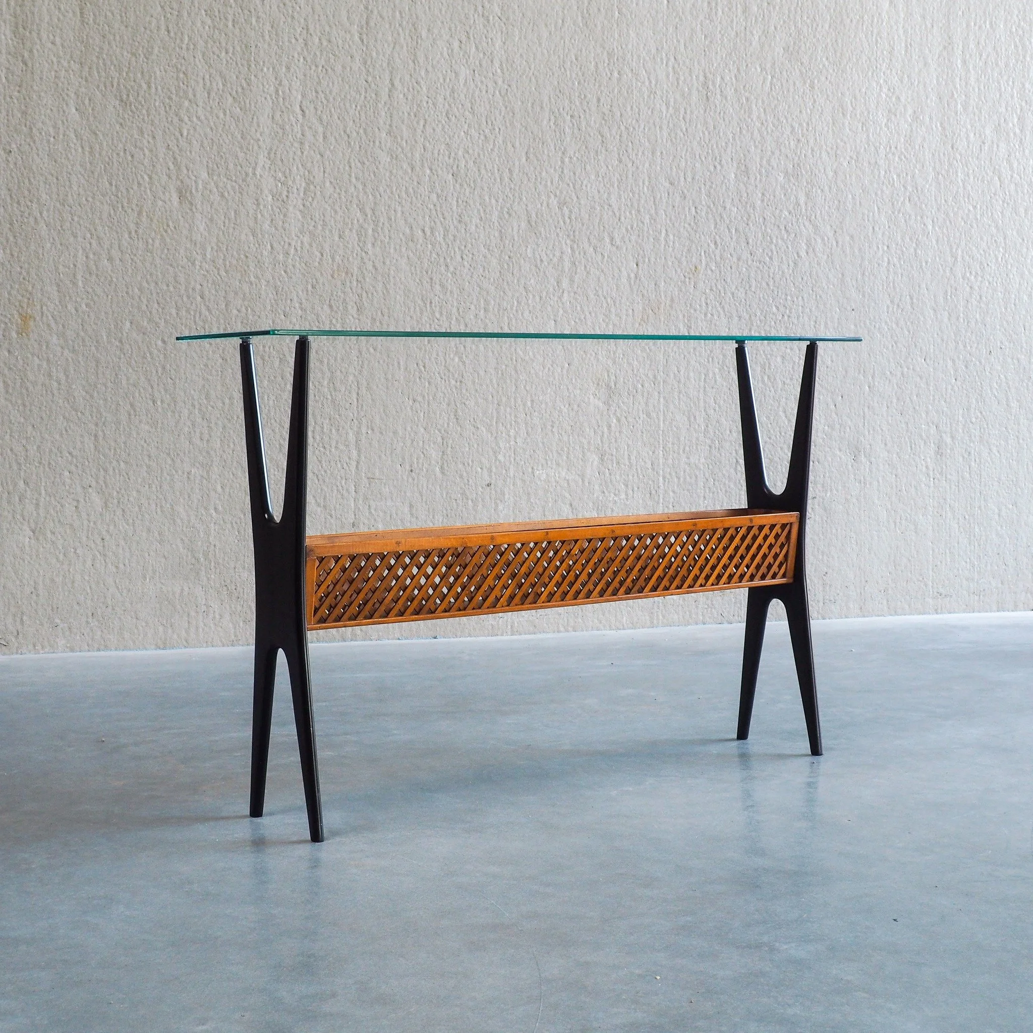 1950s Italian Ebonized Console Table with Glass Top &amp; Lattice Basket 

An exceptional 1950s Italian Mid-Century Modern console table featuring sculptured, dynamic lines and high-quality craftsmanship.This piece showcases dramatic, ebonized bentwo